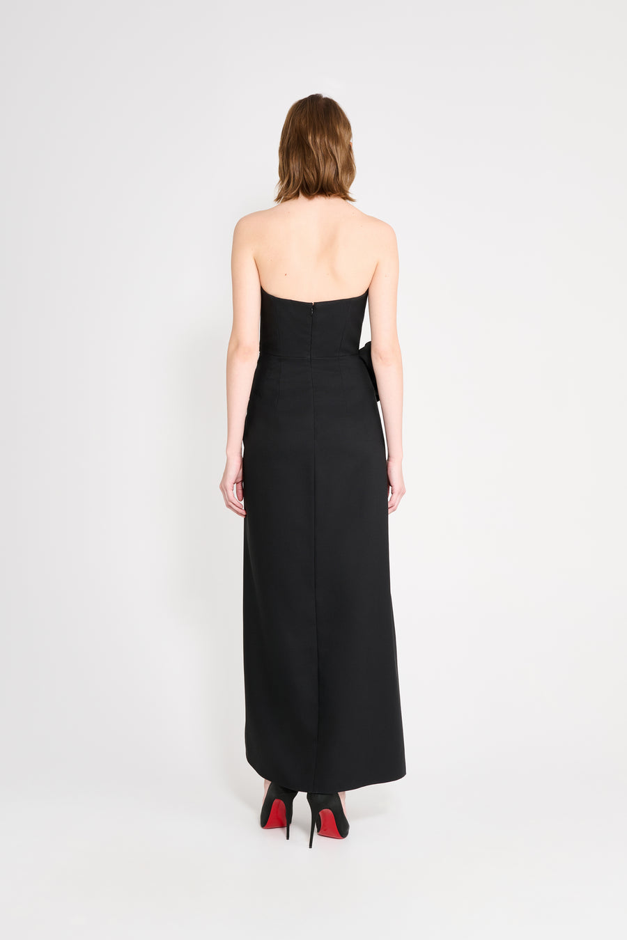 Woman wearing a black strapless dress on a white background