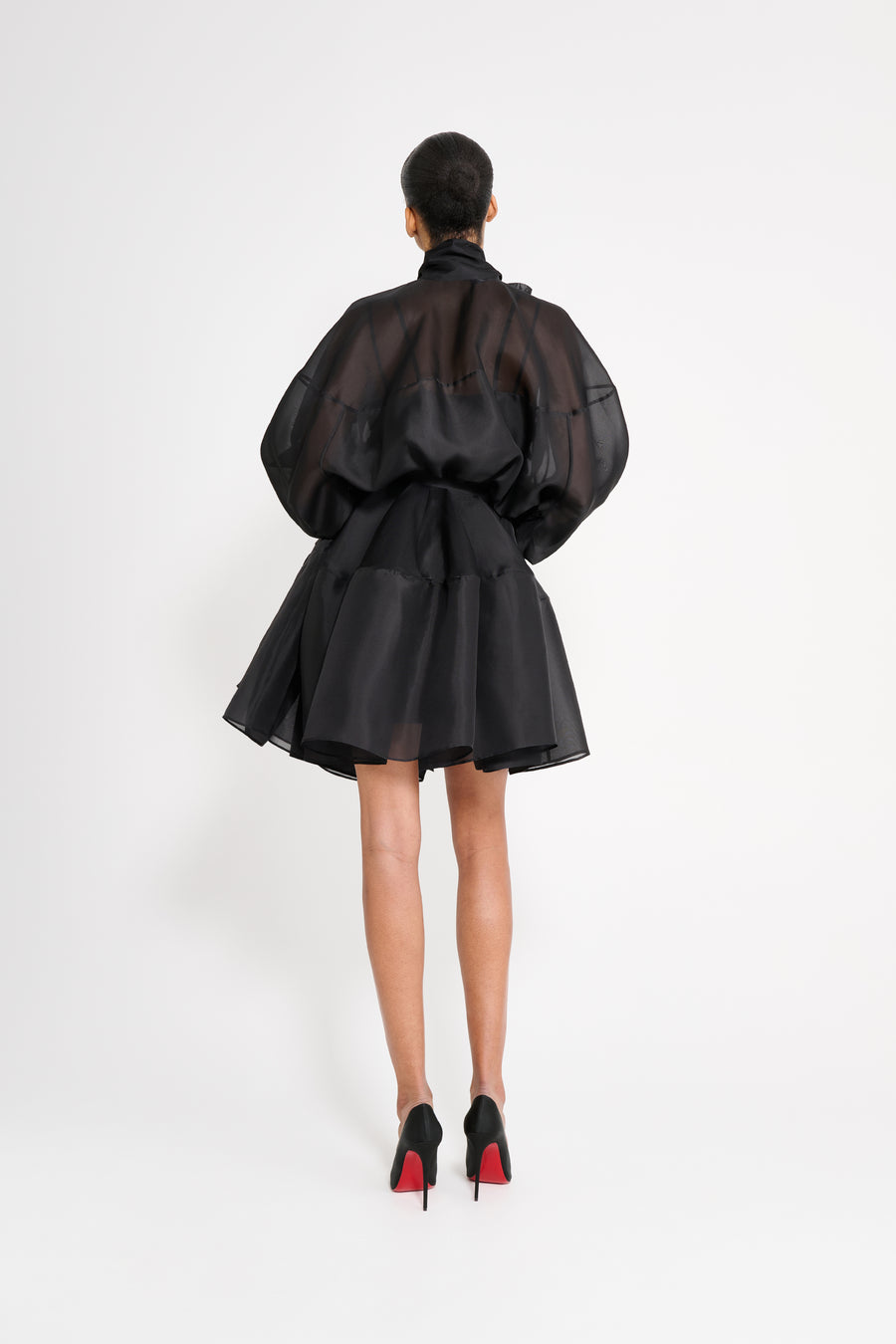 Person wearing a black outfit with sheer elements on a white background