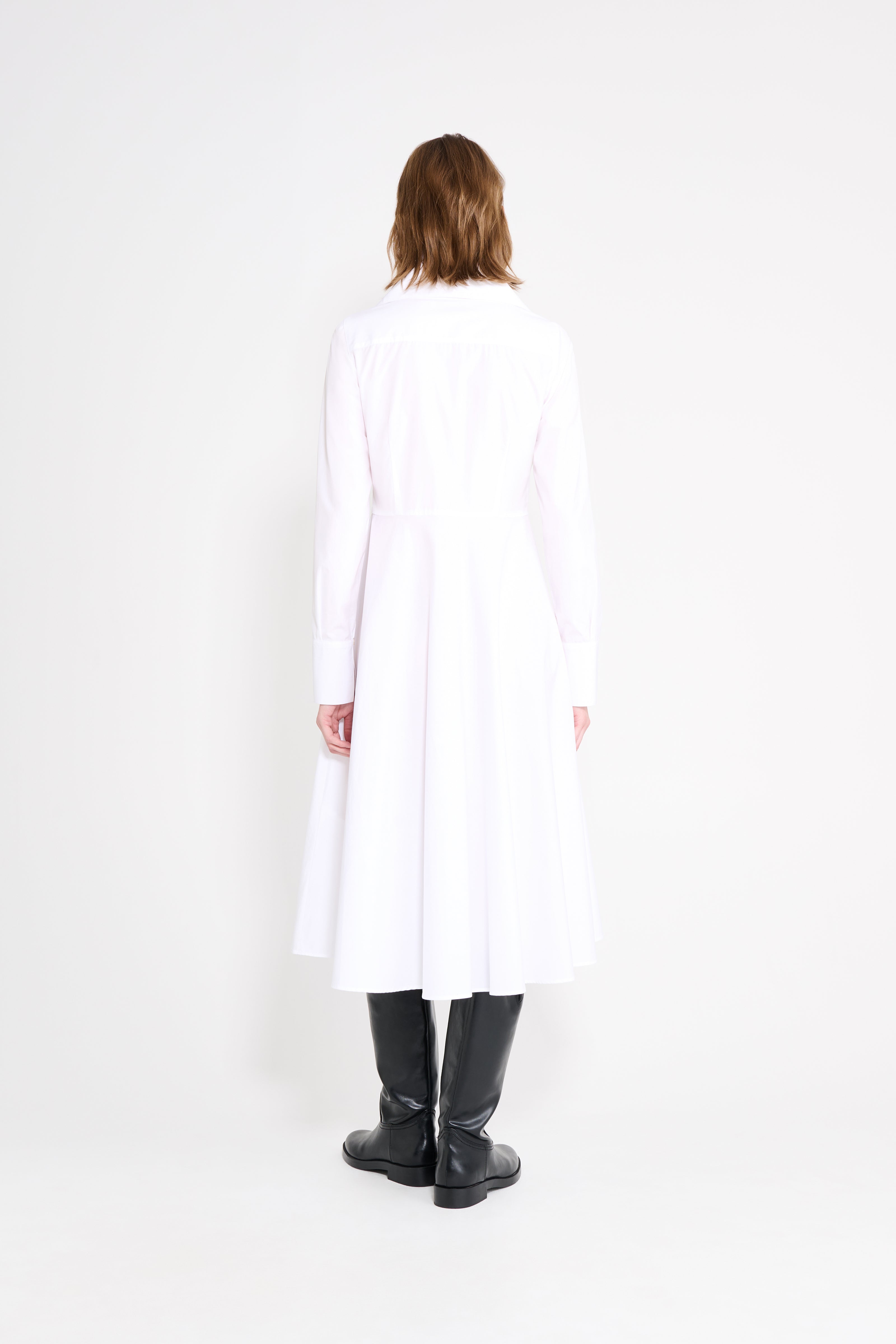 Person wearing a long white coat and black boots on a white background