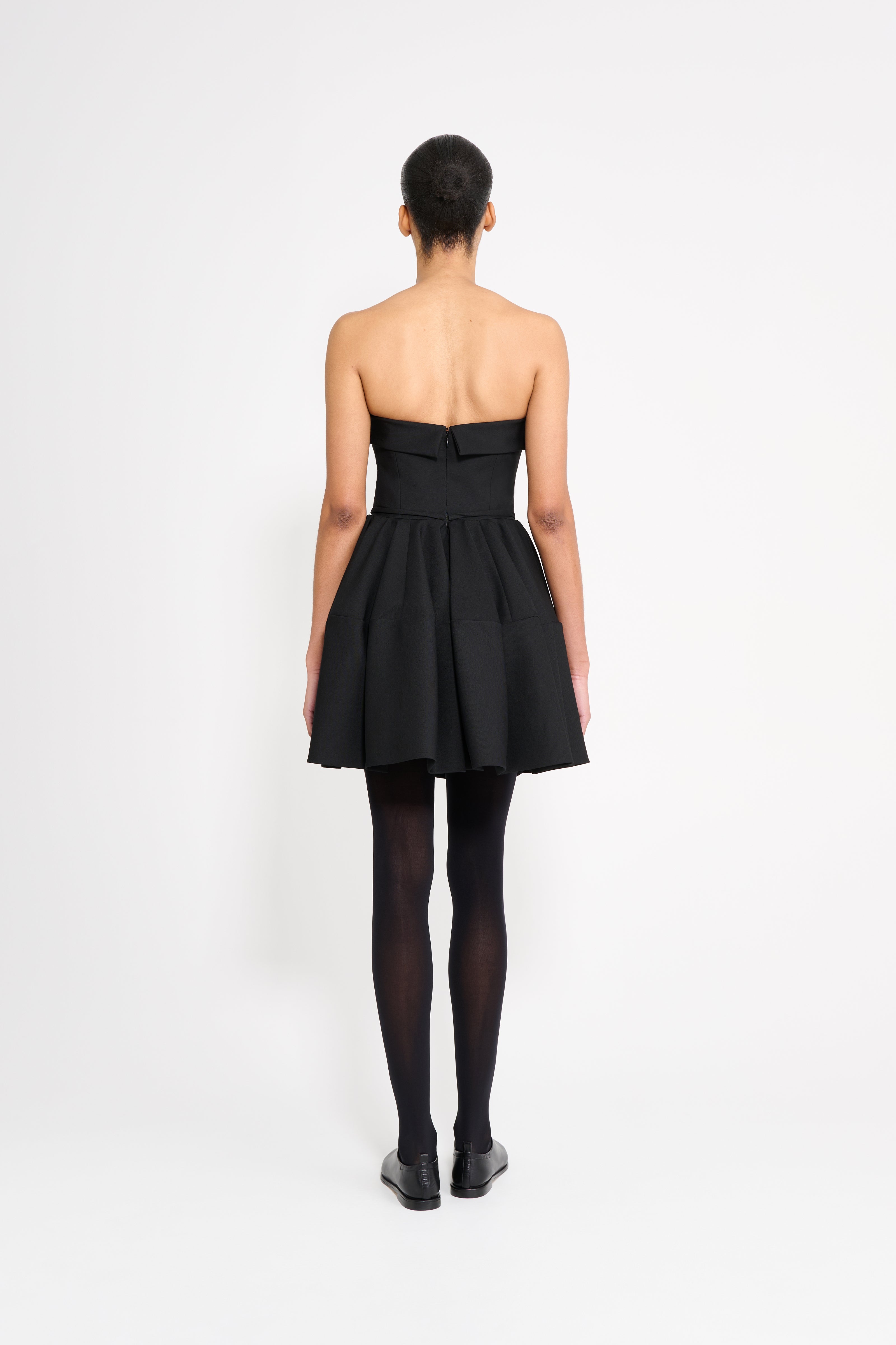 Person wearing a black strapless dress on a white background