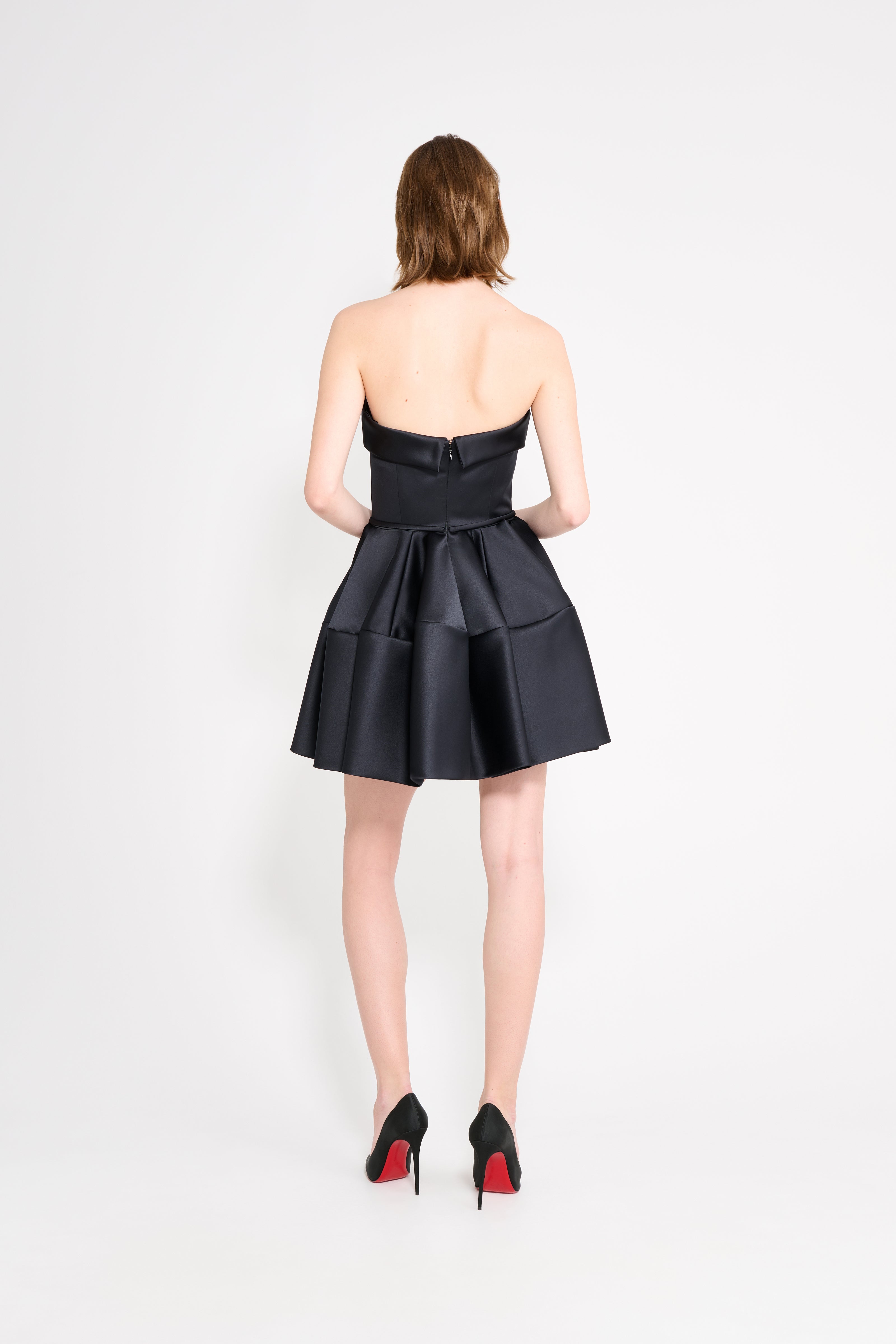 Model wearing a black mini dress on a white background.