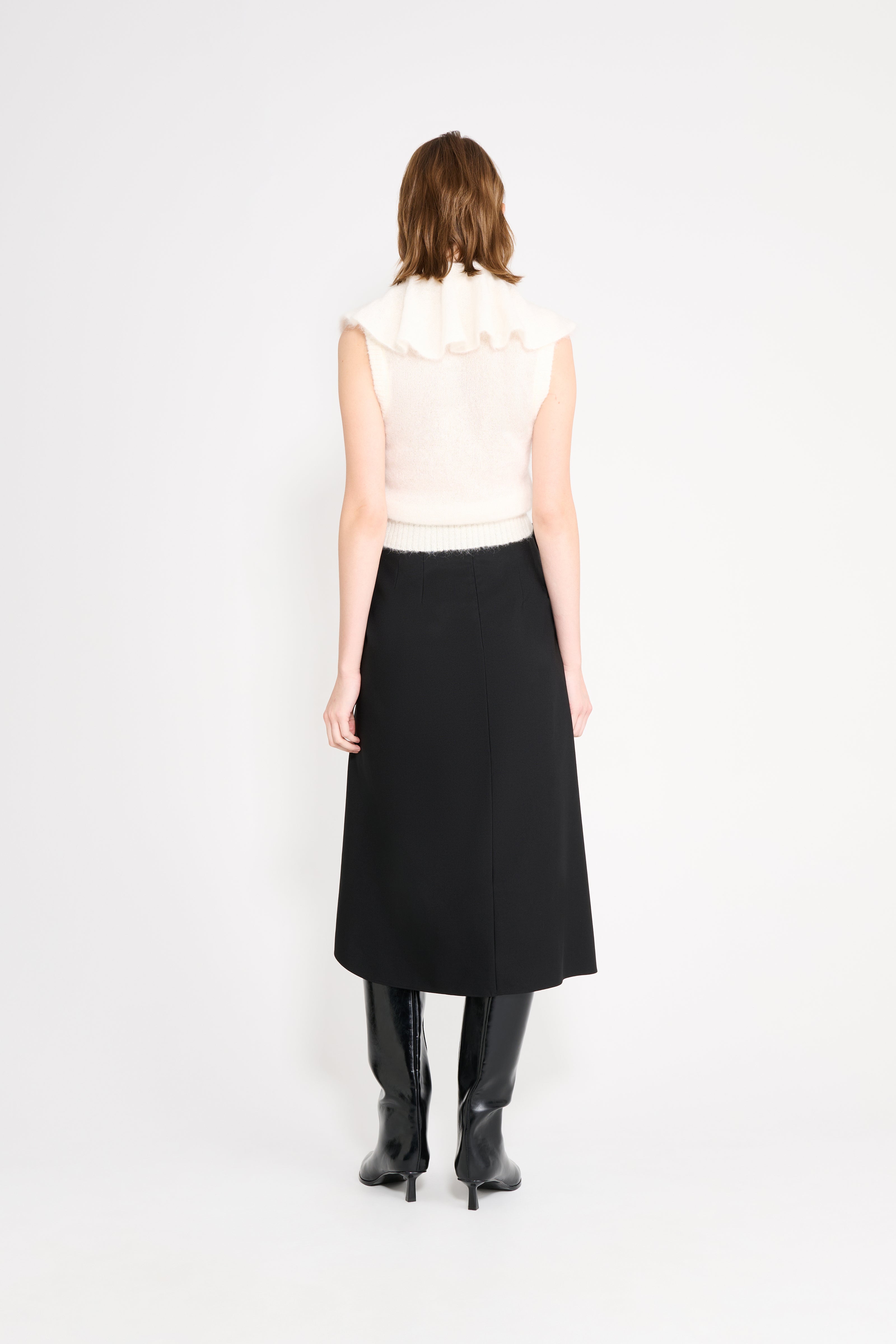 Model wearing a white volant neck top shown from the back.