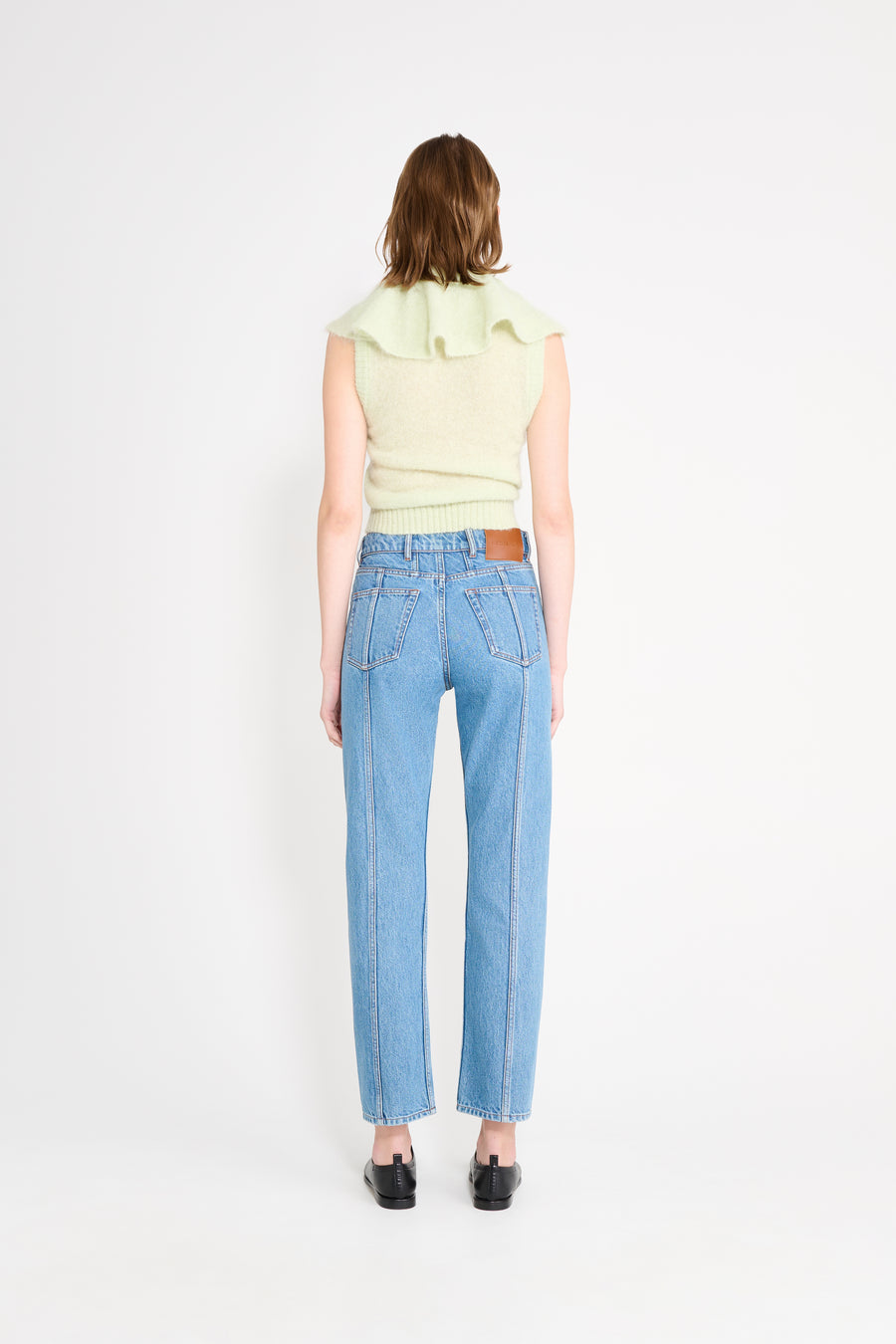 Model wearing mint volant neck top shown from the back.