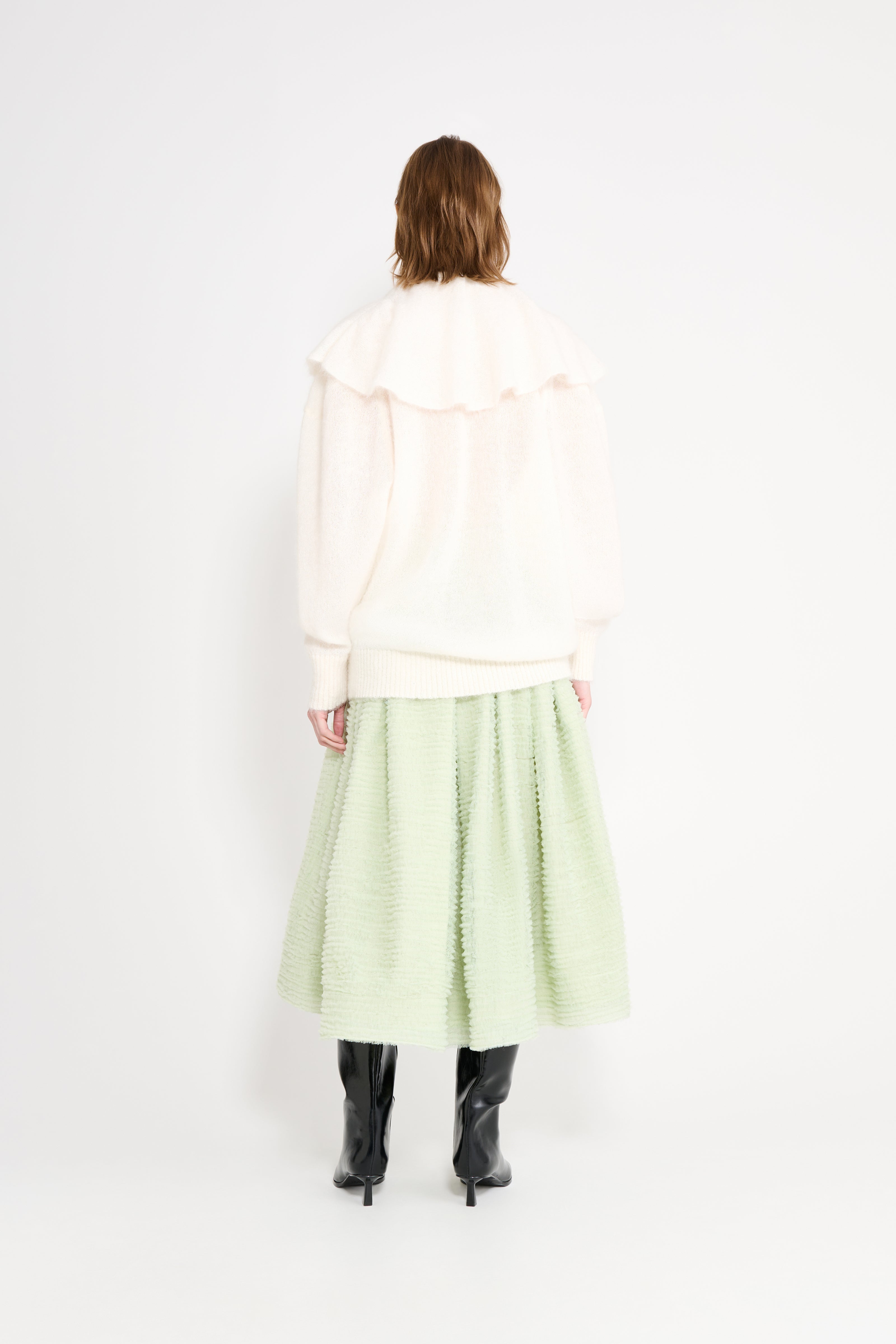 Model wearing a white volant sweater shown from the back.