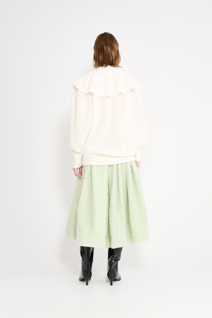 Model wearing a white volant sweater shown from the back.