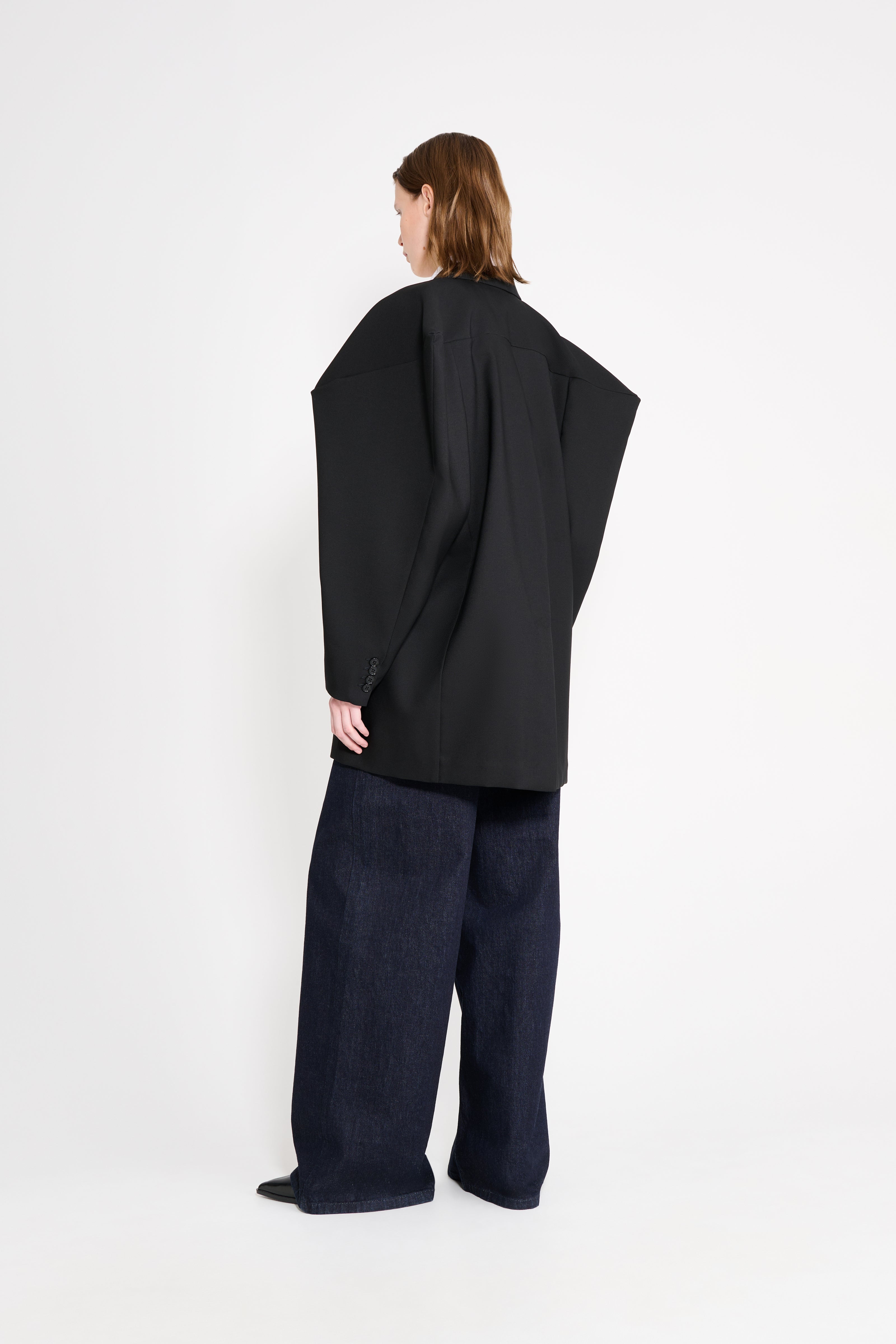 Model wearing a black square blazer shown from the back.