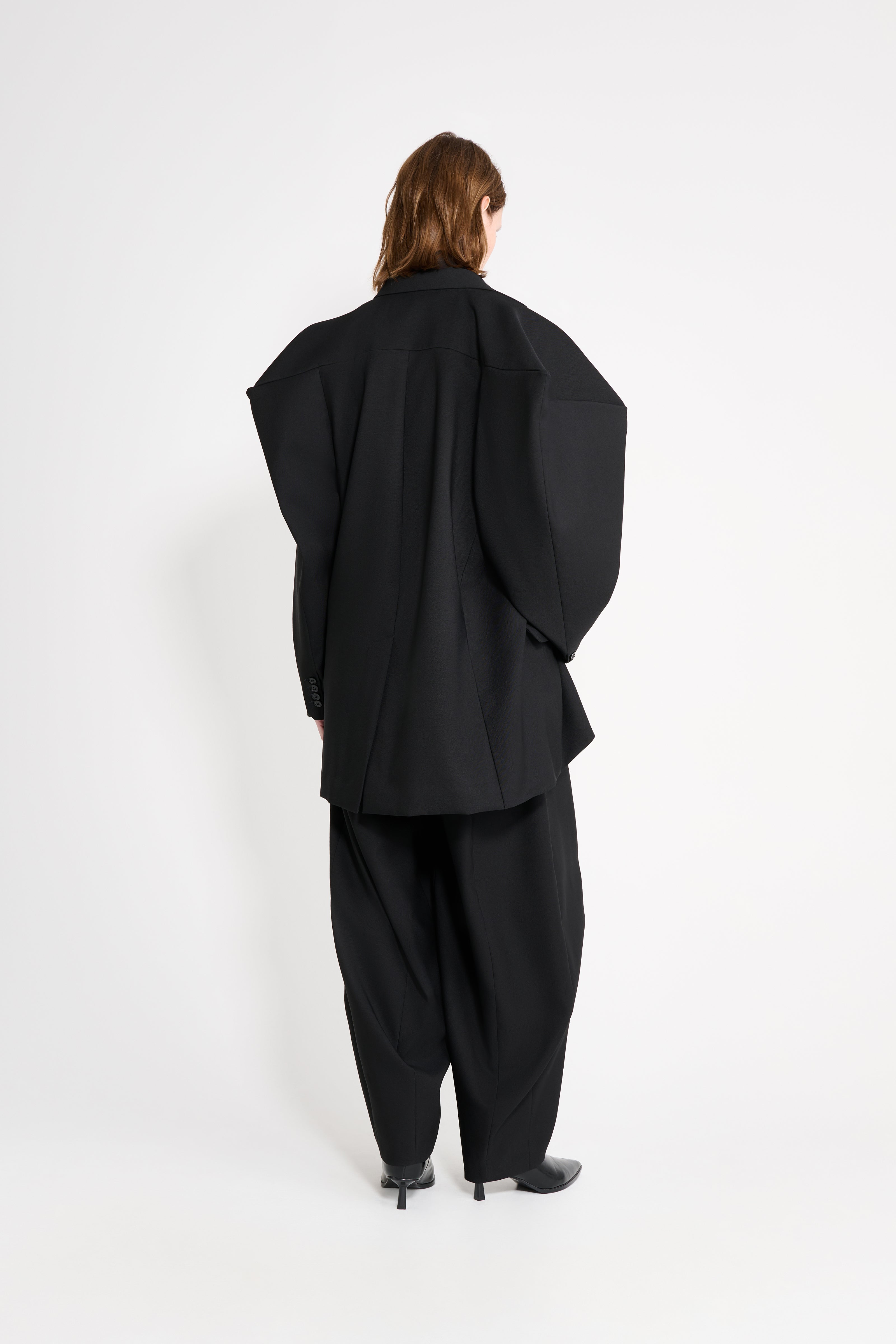 Model wearing a black square blazer shown from the back.