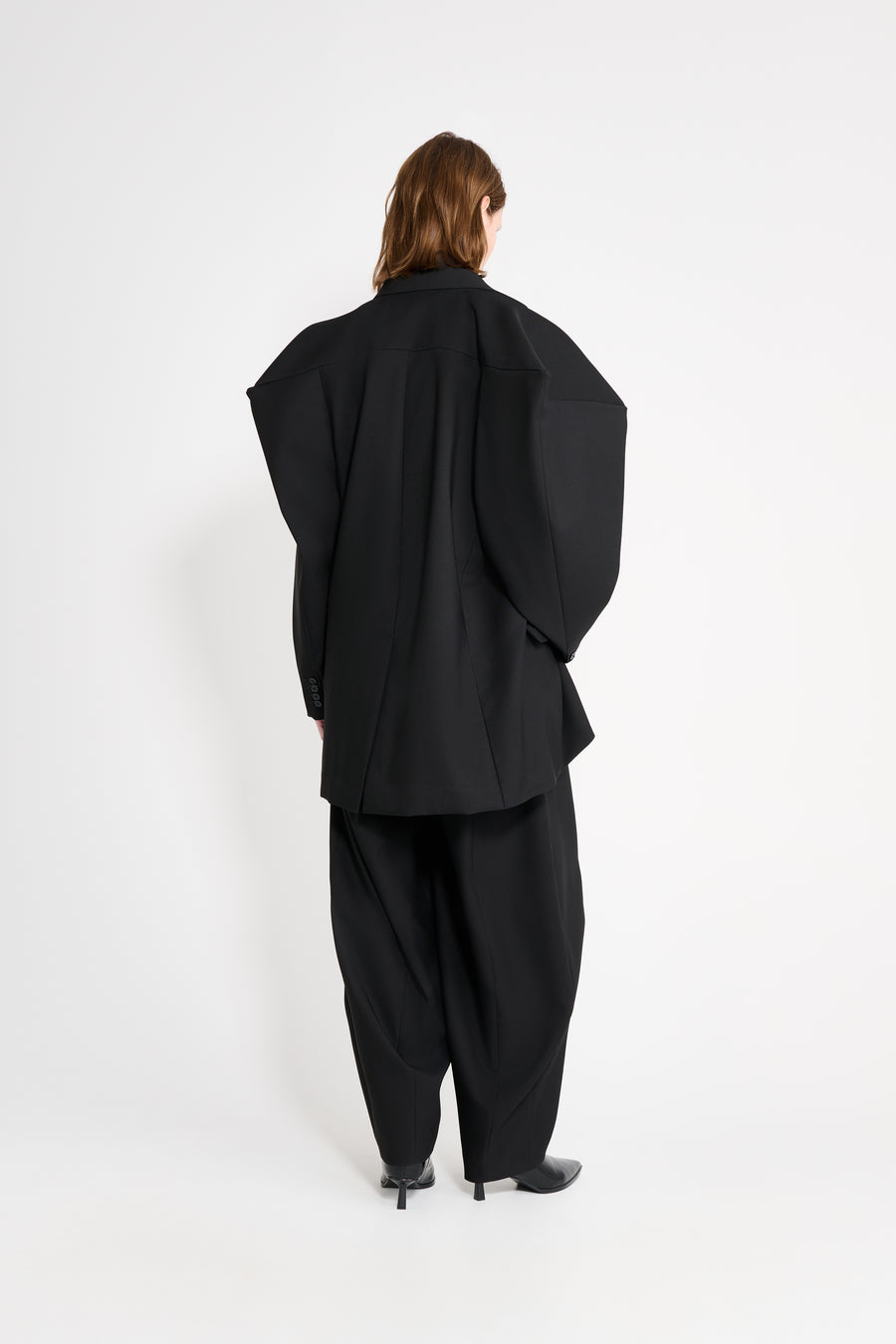 Model wearing a black square blazer shown from the back.