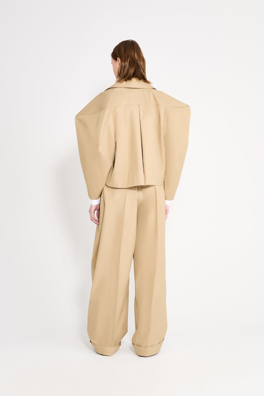 Person wearing a beige suit on a white background