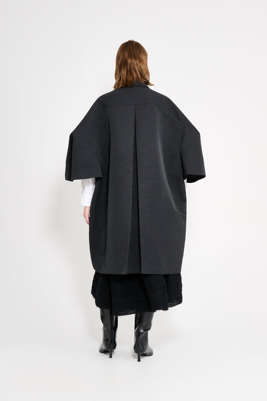 Person wearing a long black coat on a white background