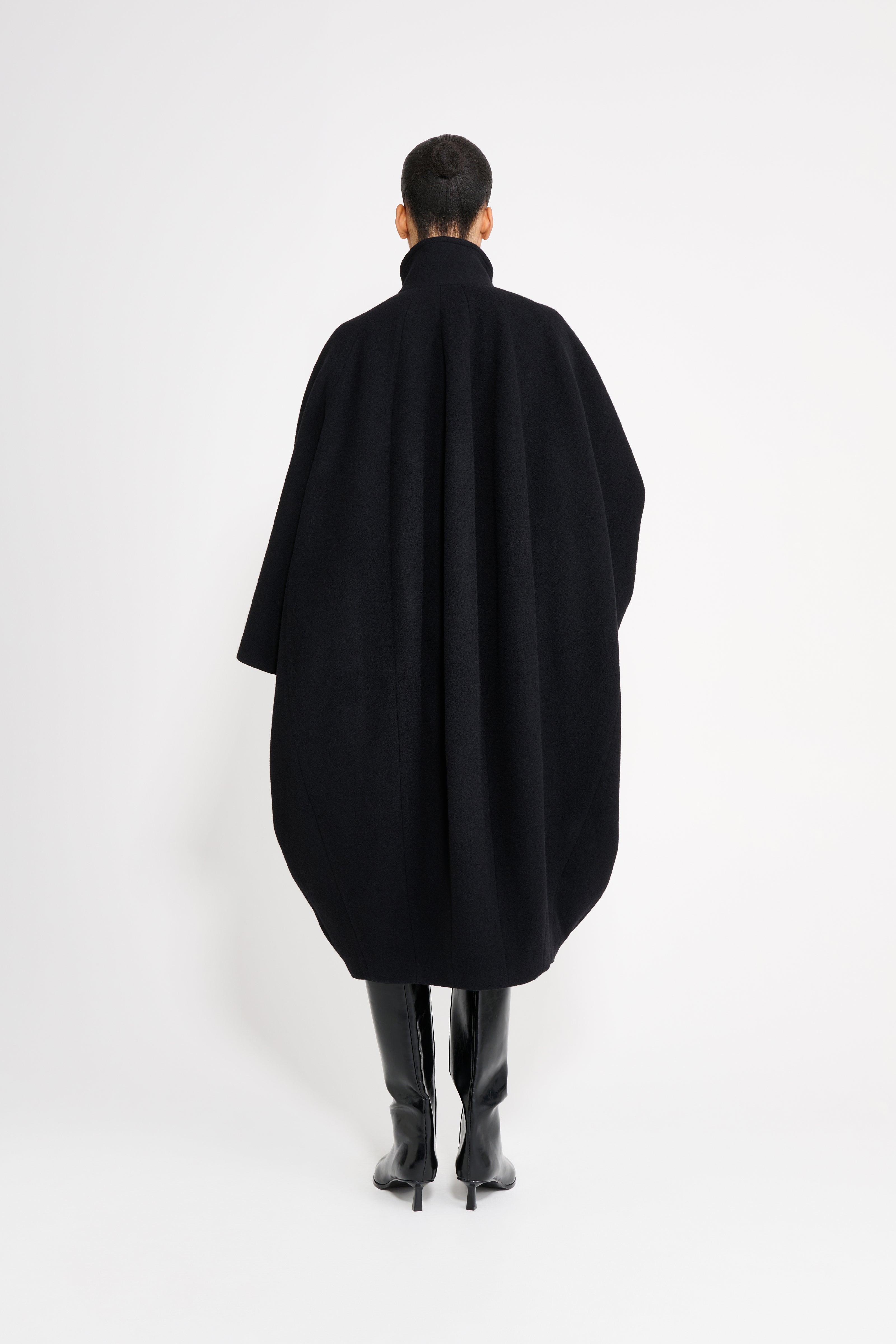Person wearing a black coat from behind on a white background
