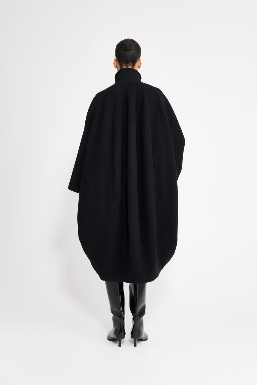 Person wearing a black coat from behind on a white background
