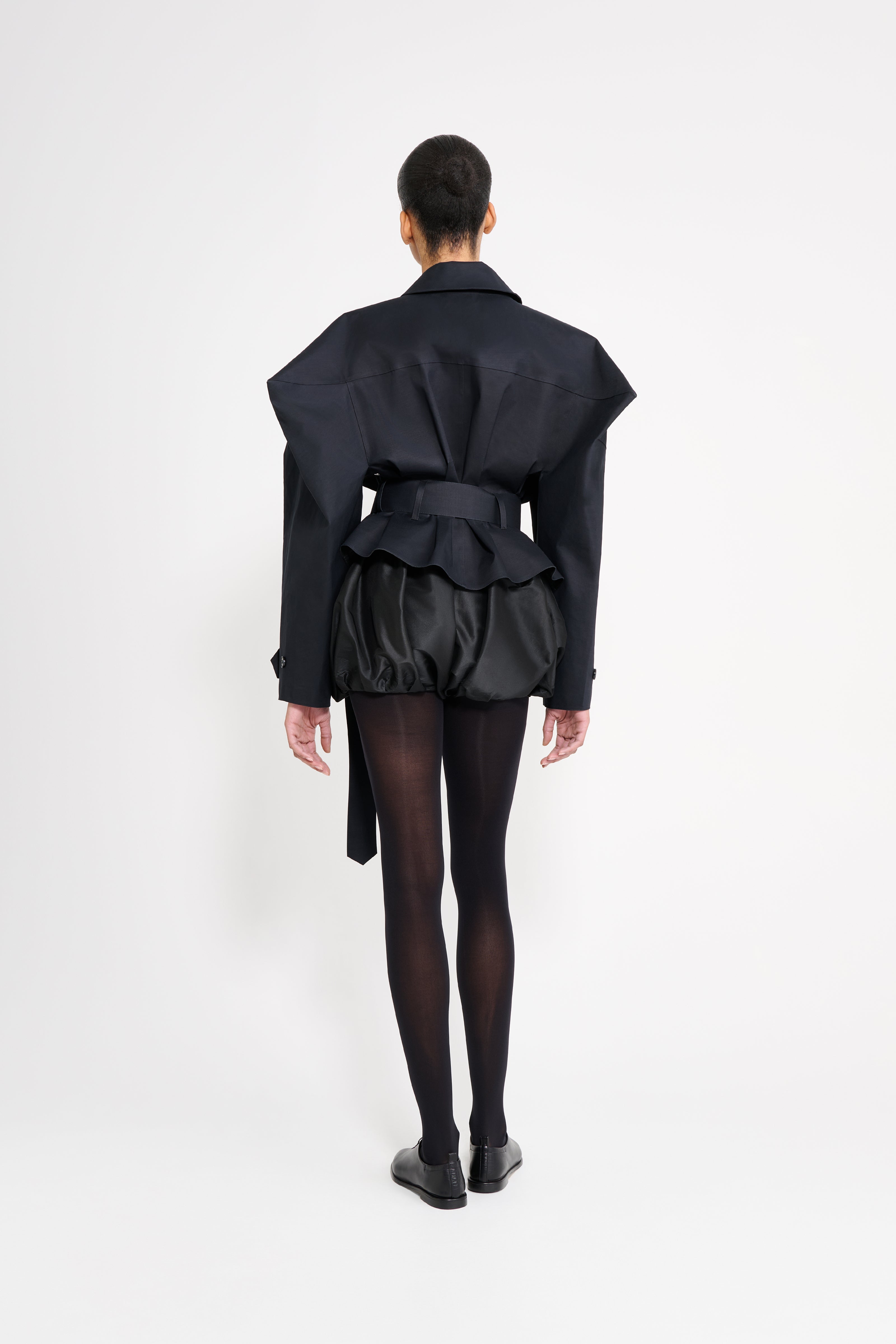 Person wearing a black outfit with a jacket and pants on a white background