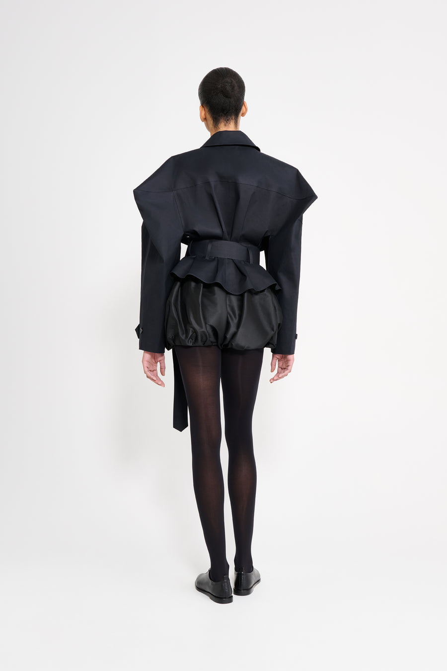 Person wearing a black outfit with a jacket and pants on a white background