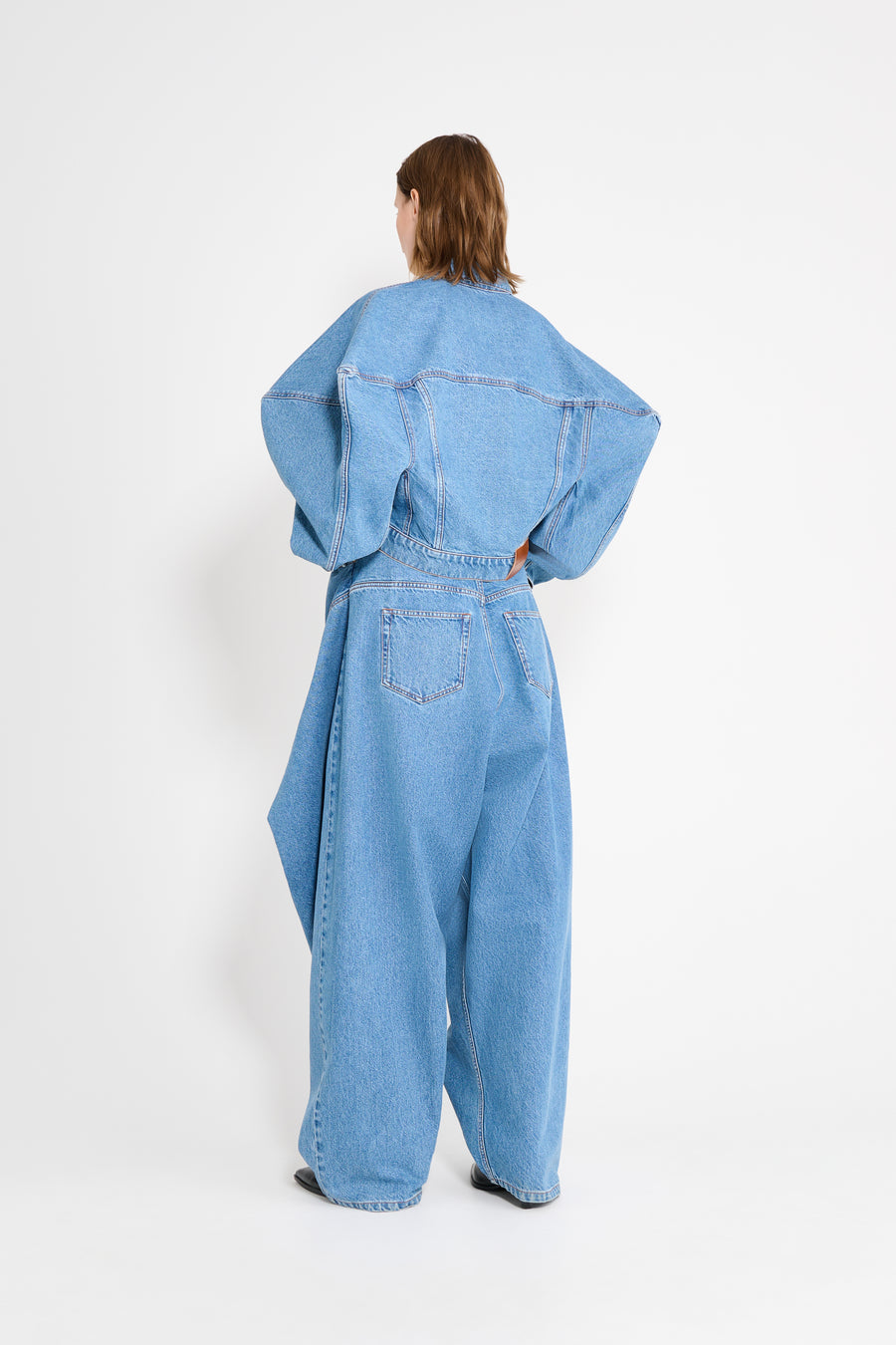 Person wearing a blue denim jumpsuit on a white background