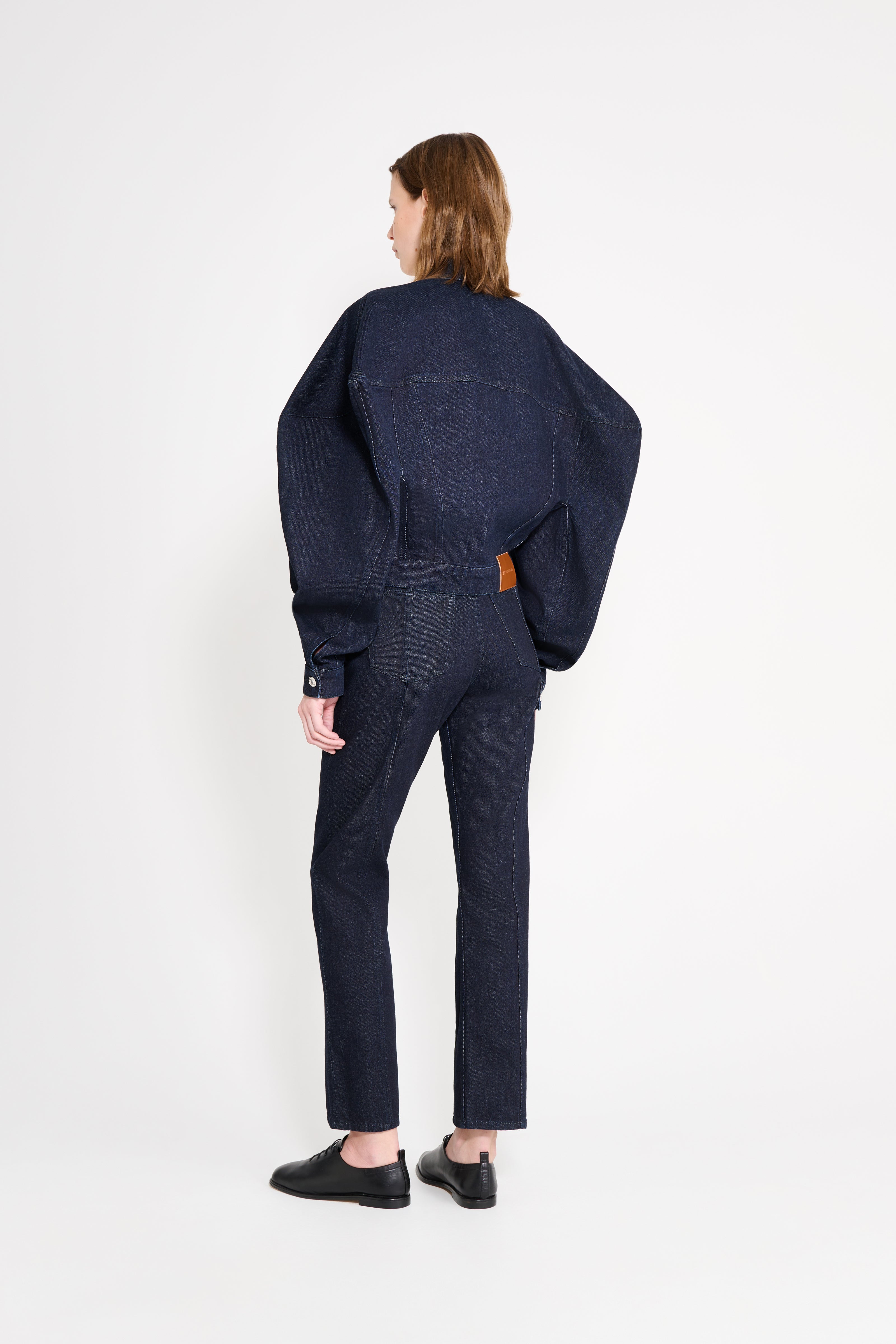 Person wearing a dark denim outfit on a white background