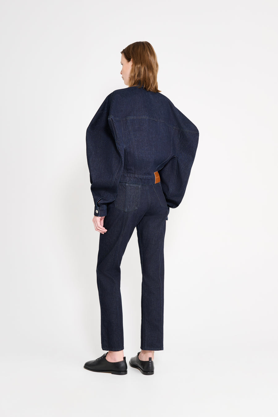 Person wearing a dark denim outfit on a white background