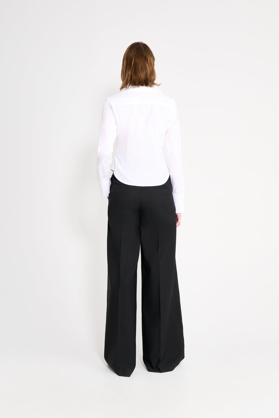Person wearing a white shirt and black pants on a white background