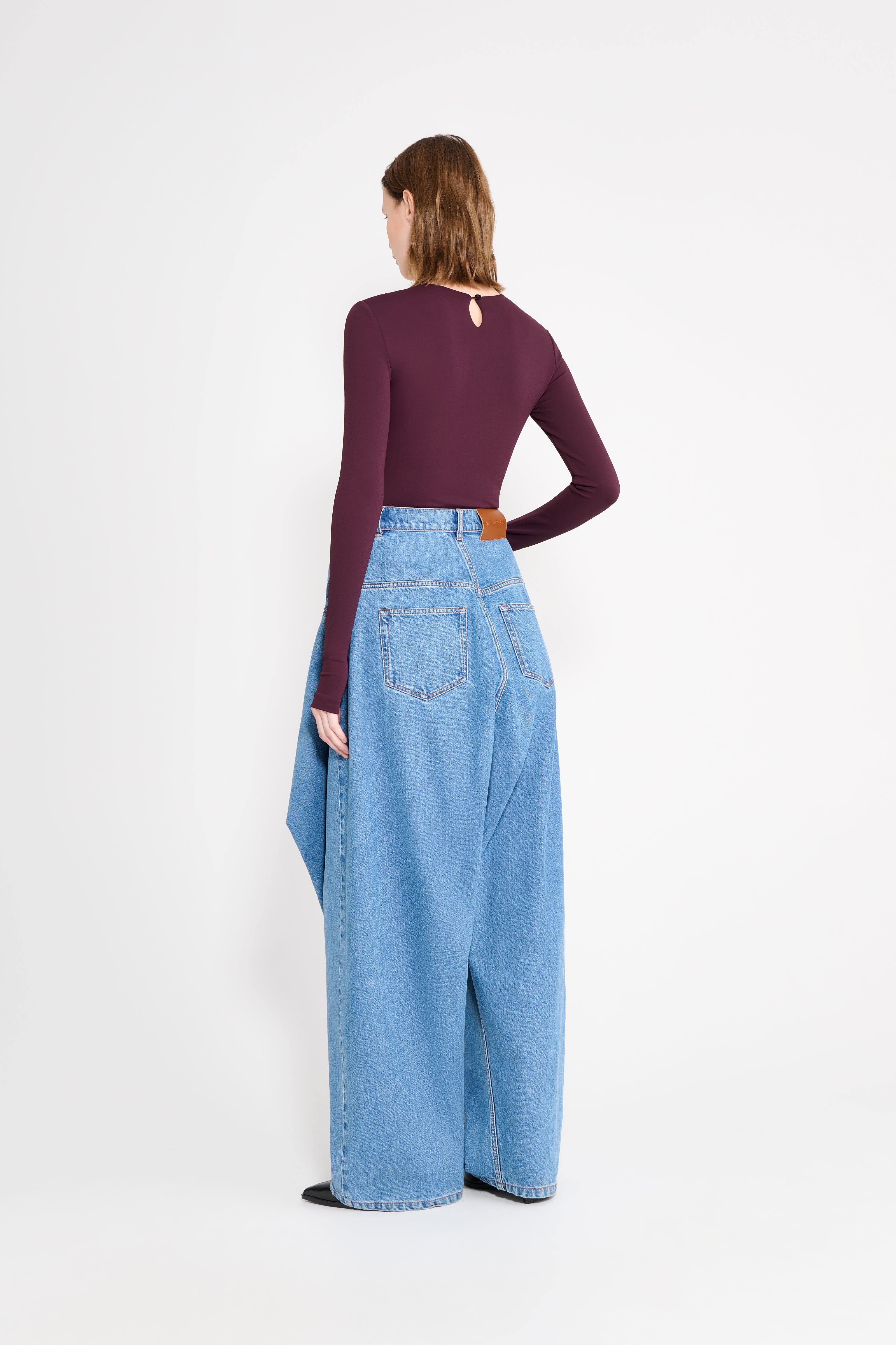 Woman wearing a purple body and light blue jeans on a white background