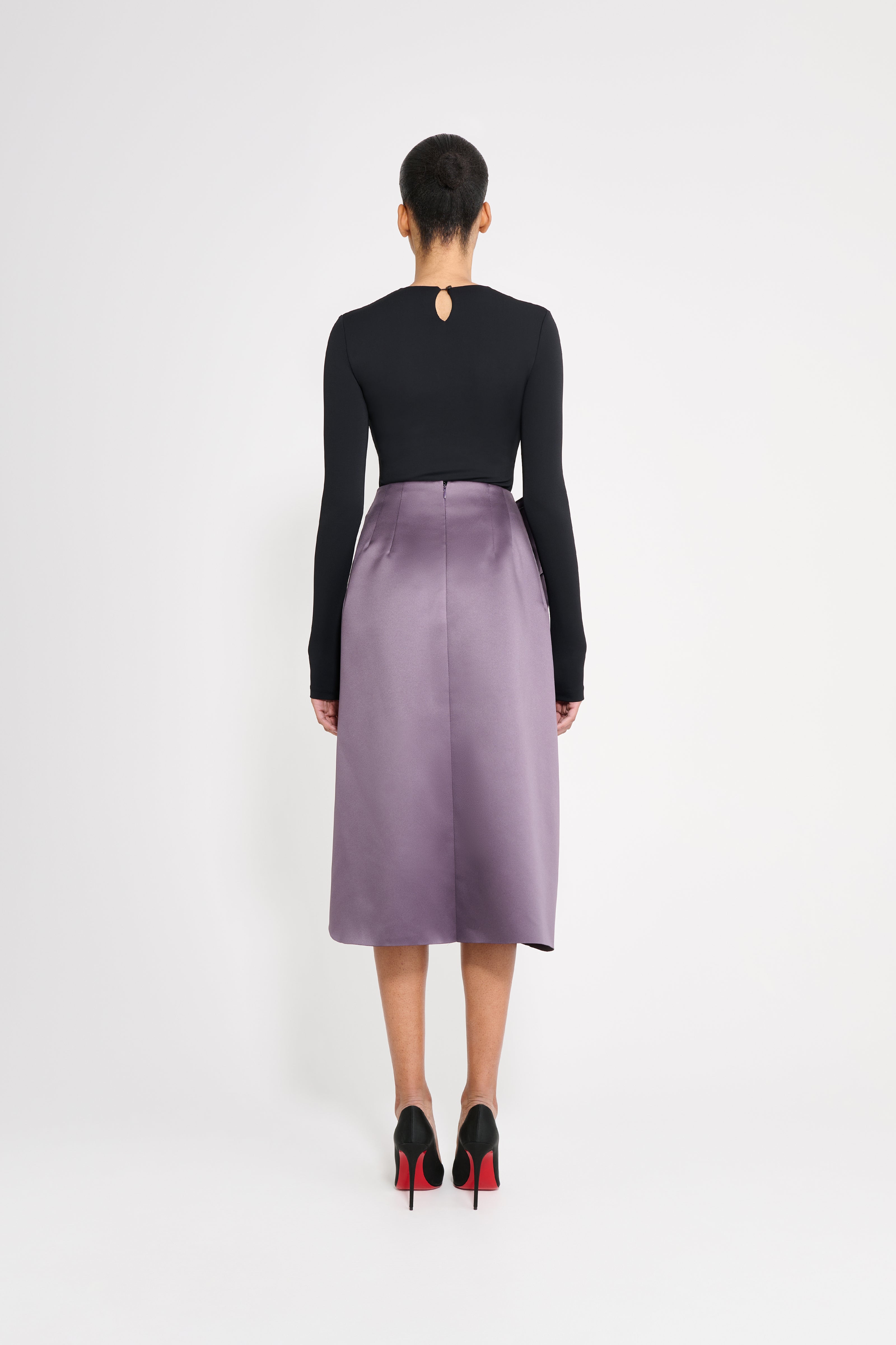 Model wearing a black body with a purple skirt on a white background.