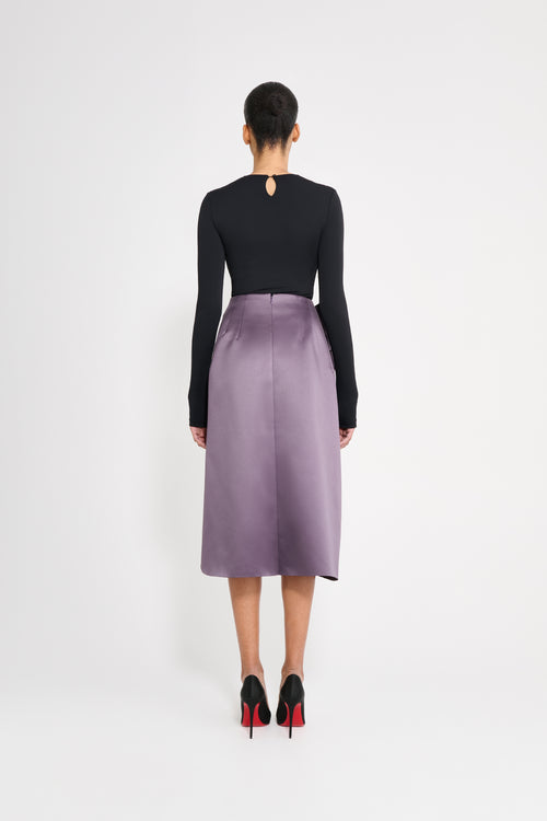 Model wearing a black body with a purple skirt on a white background.