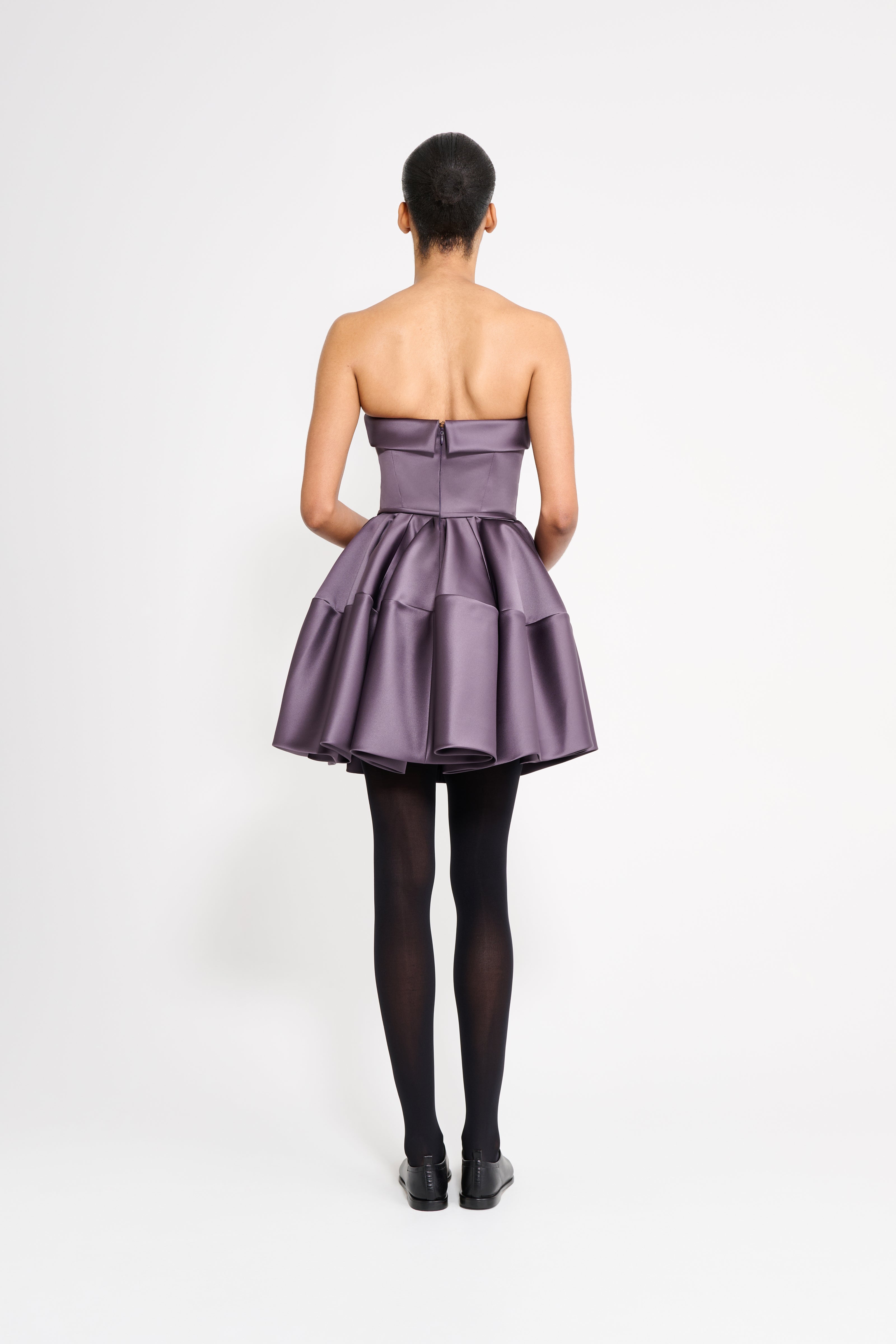 Model wearing a purple mini dress on a white background.