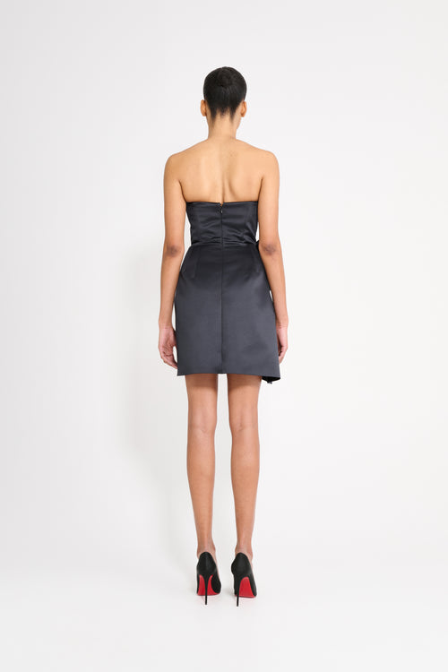 Model wearing a black mini dress on a white background.