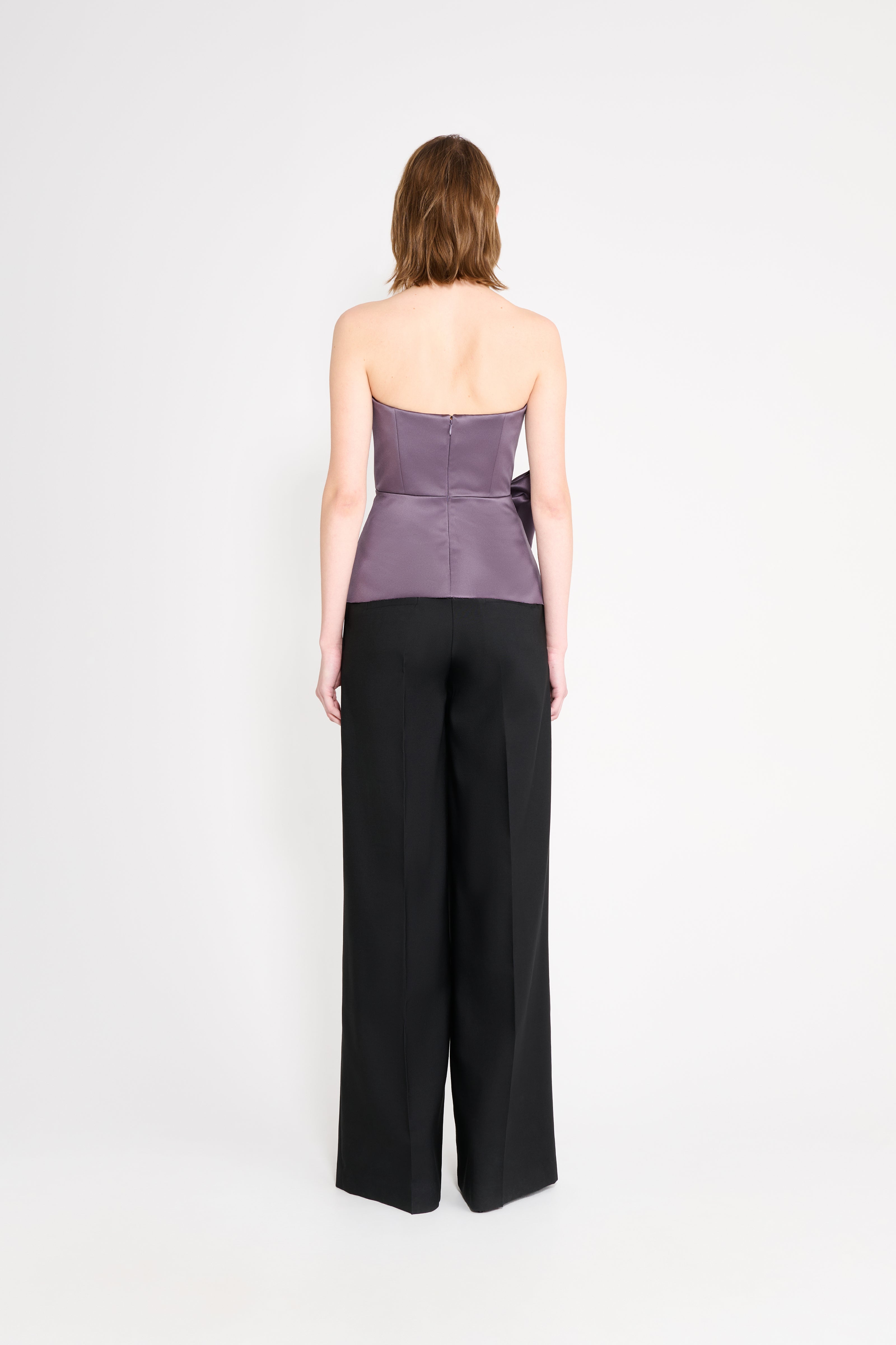 Model wearing a purple top with black pants on a white background.