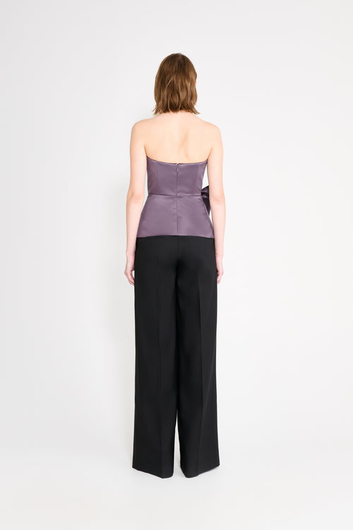 Model wearing a purple top with black pants on a white background.