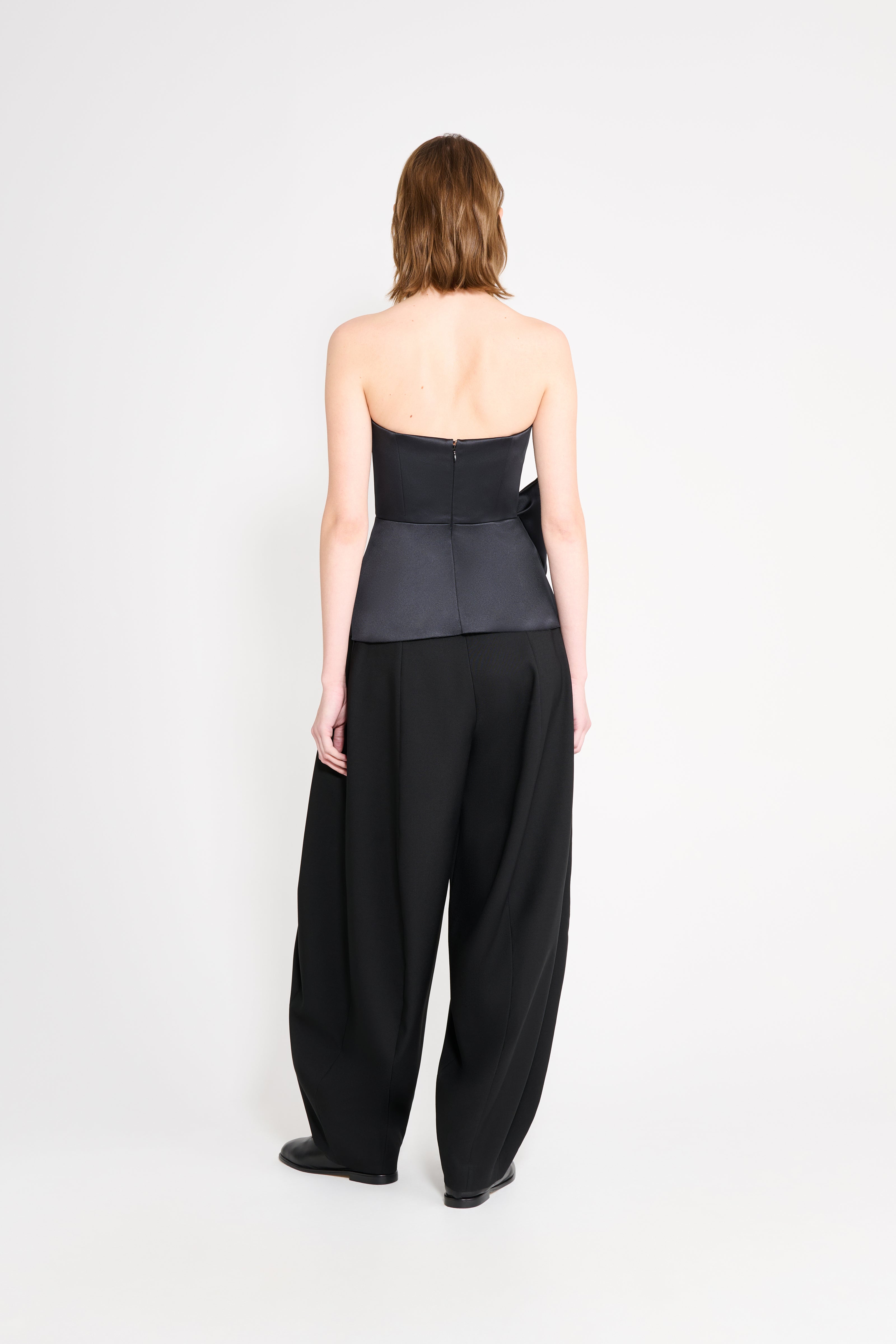 Model wearing a black top with black pants on a white background.