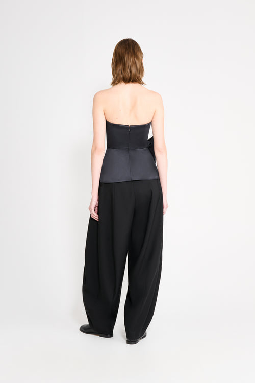 Model wearing a black top with black pants on a white background.