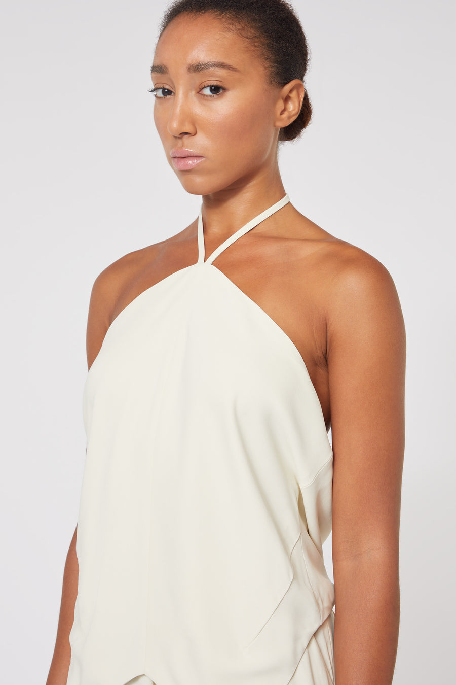 Halter neck top in ivory fabric, featuring a sleek and minimalist design with a smooth, flowing texture.