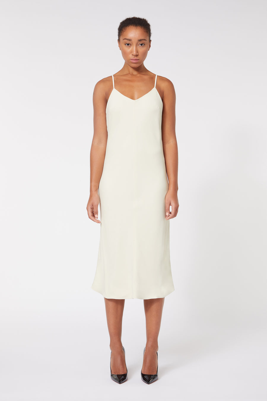 Elegant ivory slip dress with thin straps, featuring a minimalist design and knee-length cut.