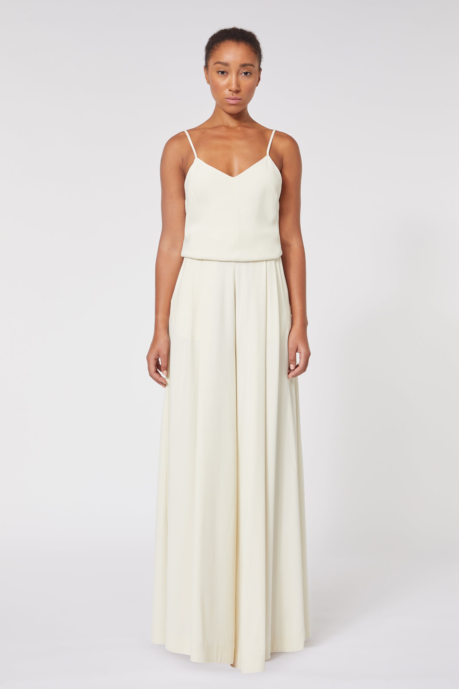 Elegant ivory sleeveless gown with delicate spaghetti straps flows gracefully, highlighting minimalist design.