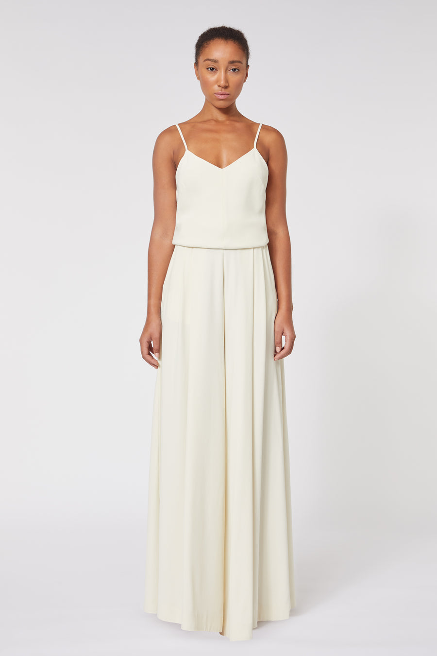 Elegant ivory sleeveless gown with delicate spaghetti straps flows gracefully, highlighting minimalist design.