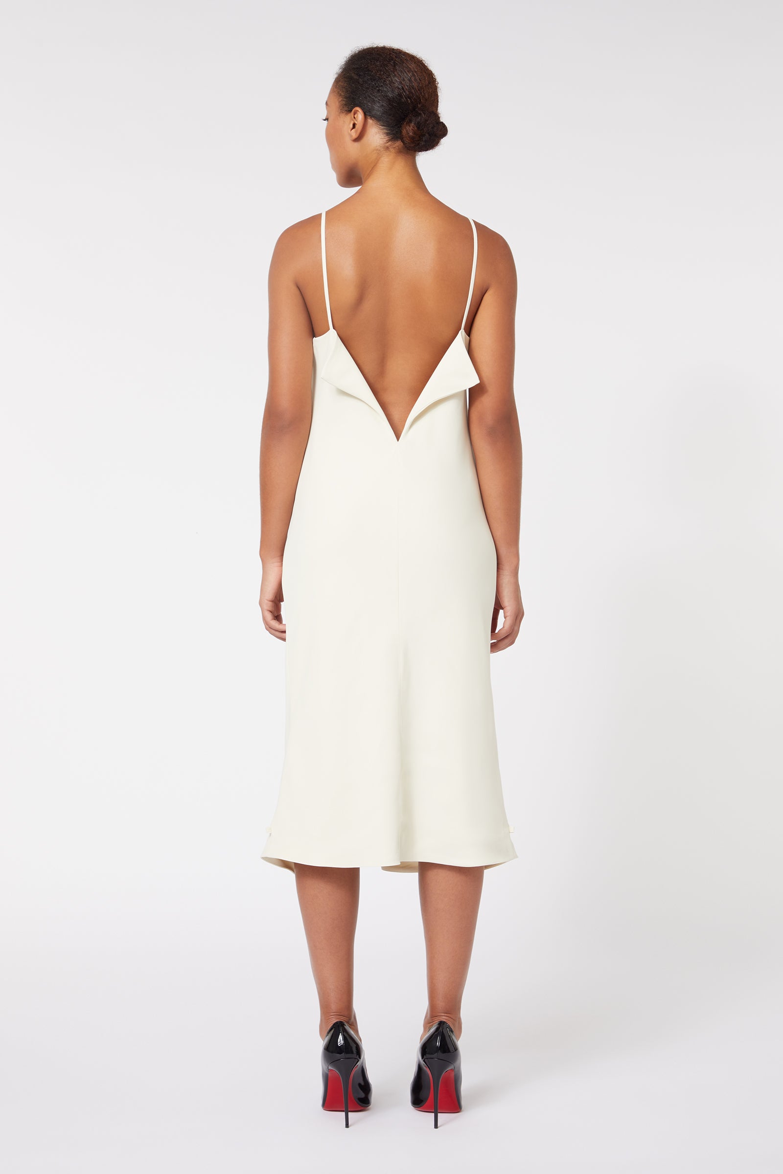 Elegant backless cream dress with sleek spaghetti straps, featuring a V-shaped plunge and midi length.