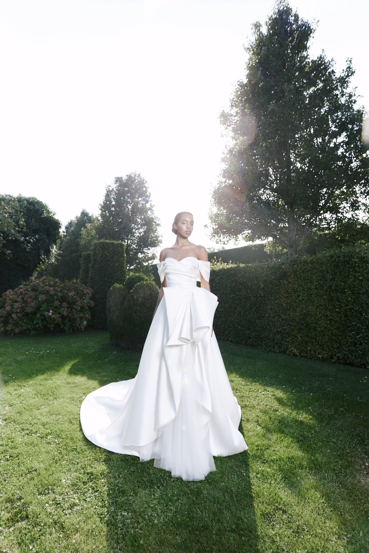 Viktor & Rolf Mariage Bridalwear Collection, Autumn Winter 25, elegant gown with sculptural design in lush garden setting.