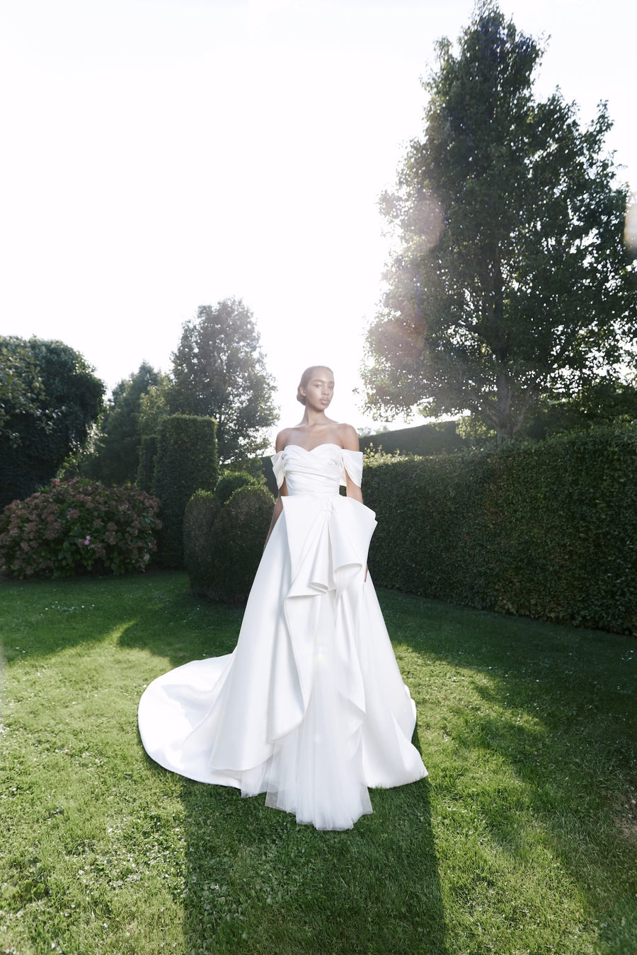 Viktor & Rolf Mariage Bridalwear Collection, Autumn Winter 25, elegant gown with sculptural design in lush garden setting.