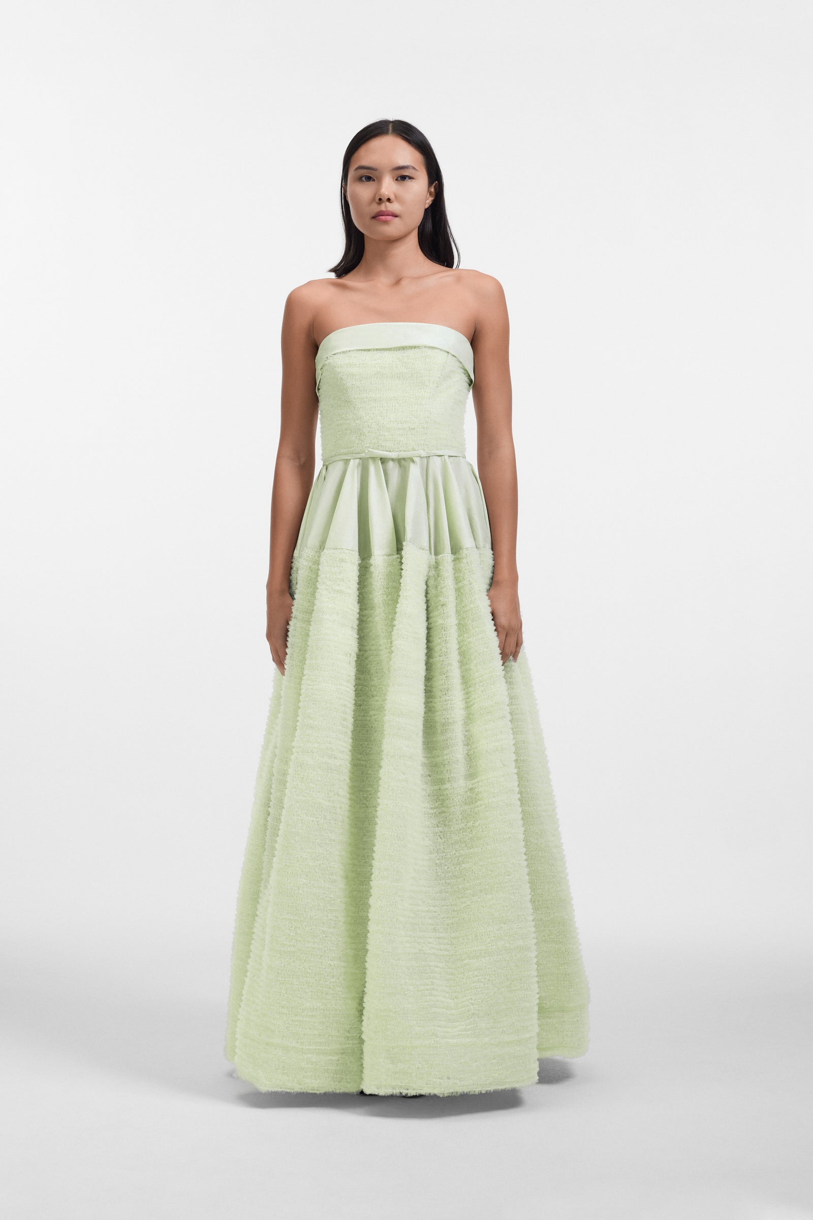 Model wearing a mint green strapless tulle gown on a white background.