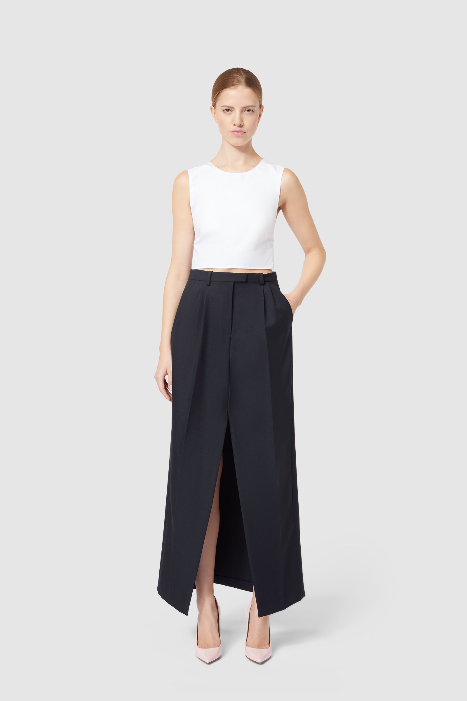 Elegant black high-waisted skirt with front slit, paired with a crisp white sleeveless top, showcasing modern minimalist style.