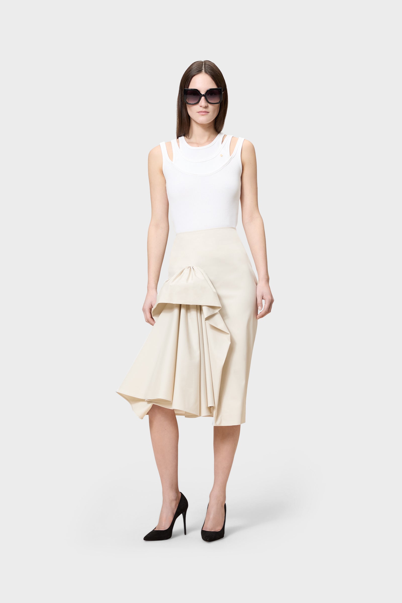 Model wearing a white multi-layered top with beige skirt on a white background.