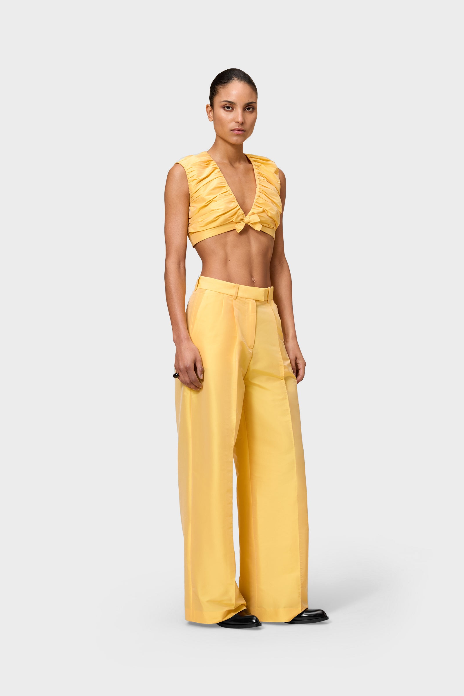 Model wearing a yellow satin set on a white background.