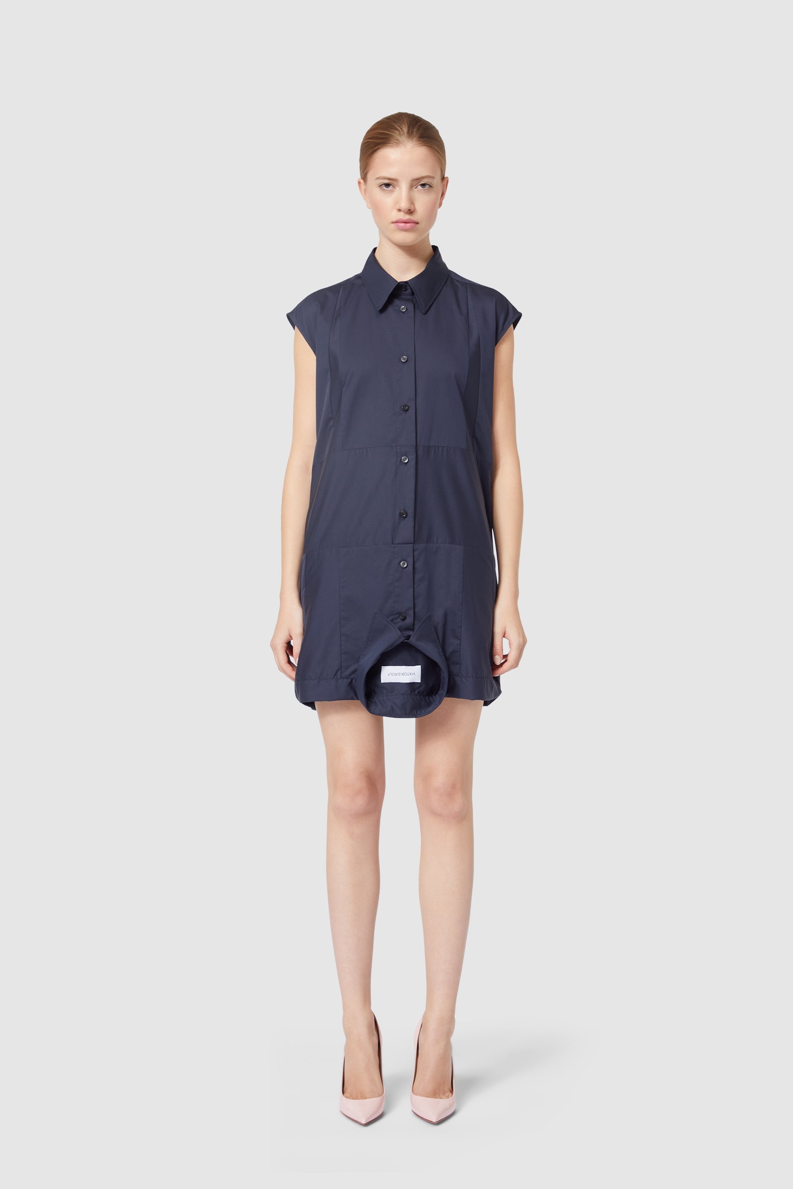 Navy blue shirt dress with short sleeves and button-down front, paired with elegant pale pink heels.