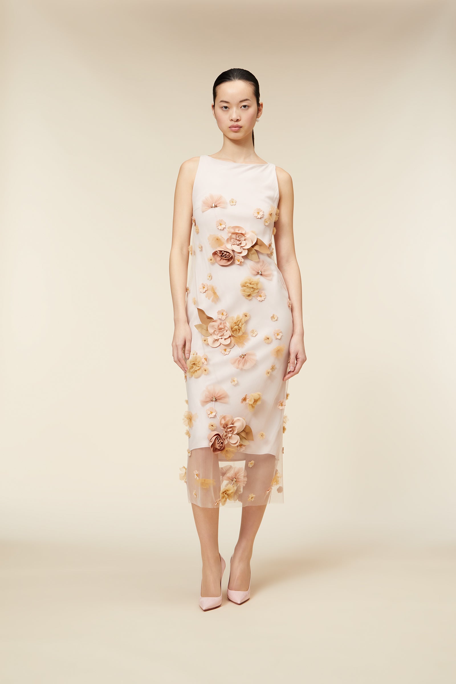 Elegant sleeveless dress with floral appliqué detailing in soft pastel tones, featuring a sheer overlay and classic silhouette.