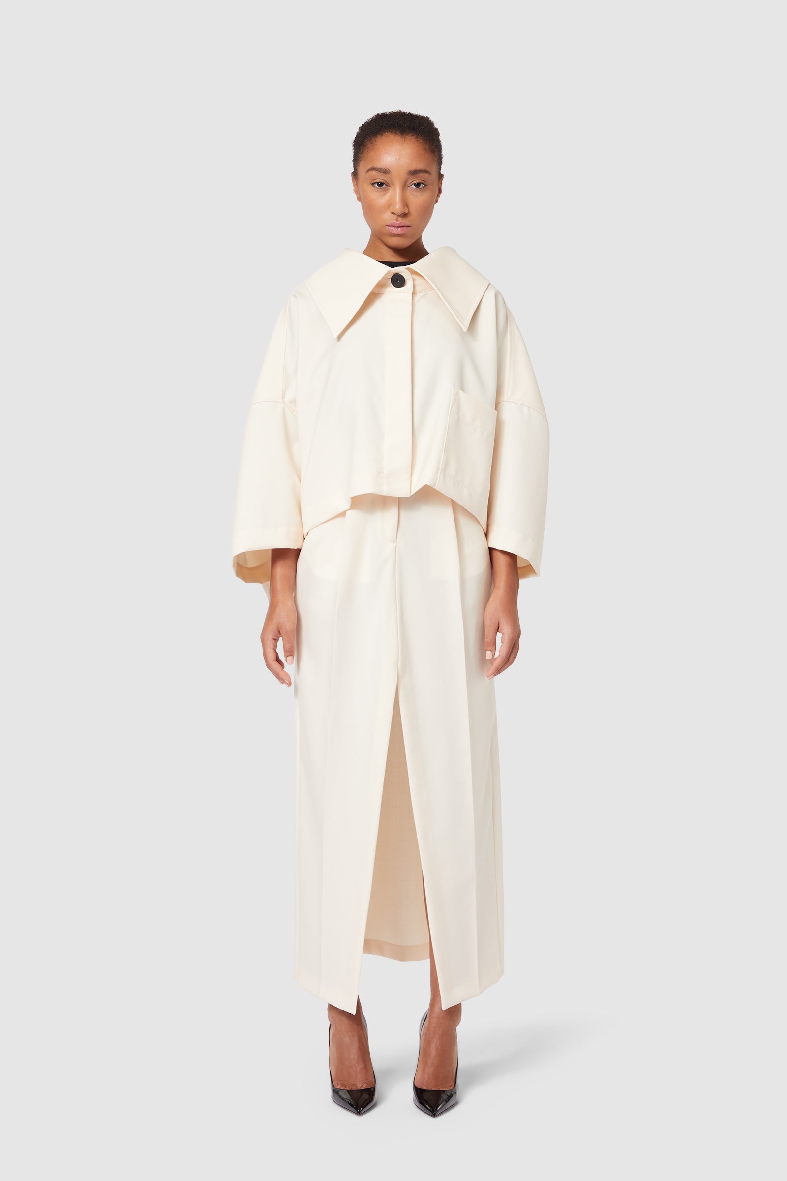 Cream-colored ensemble featuring a structured jacket with wide lapels and high-waisted skirt, exuding minimalist elegance.