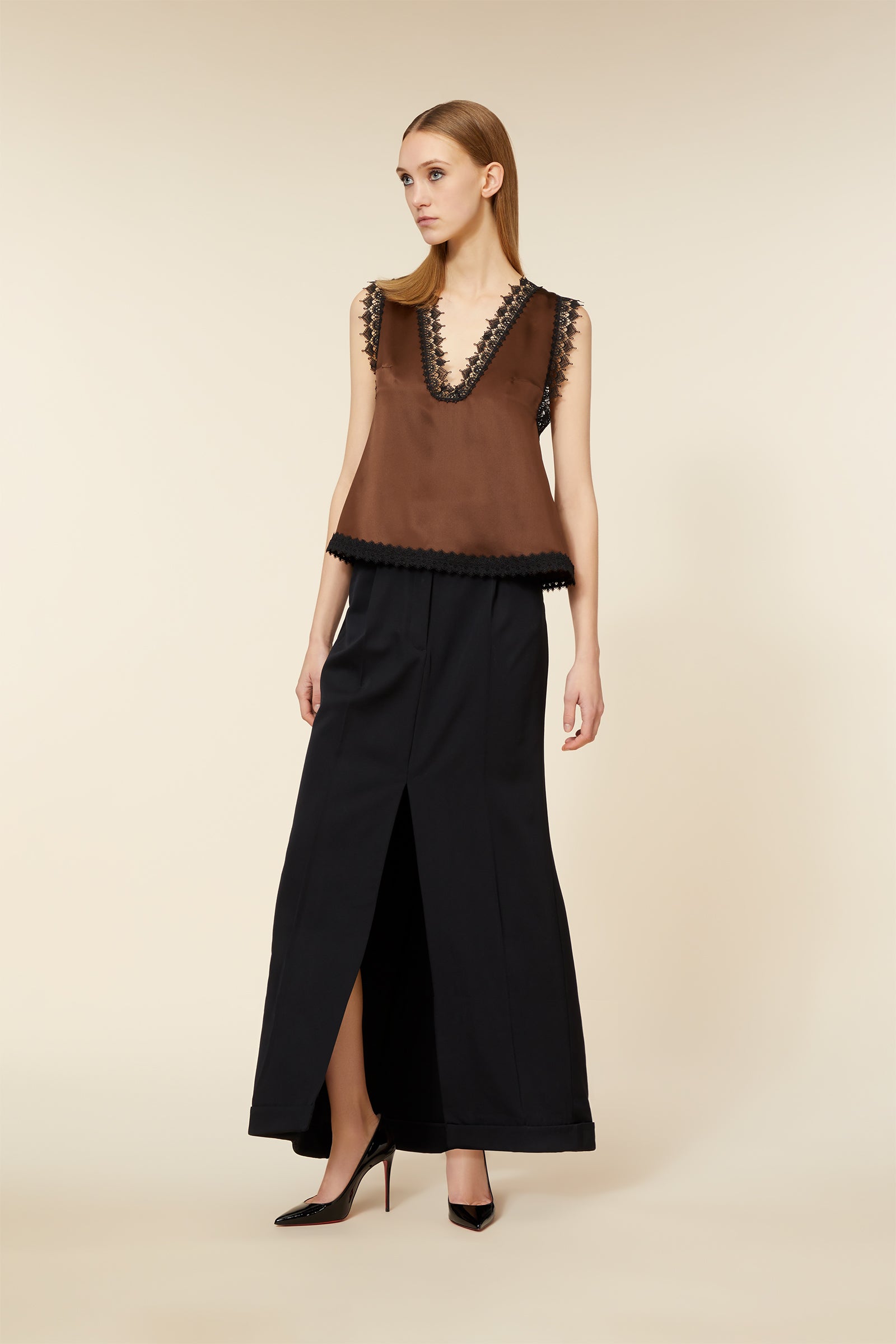 A chic brown sleeveless top with intricate lace details, paired elegantly with a long black skirt and high heels.