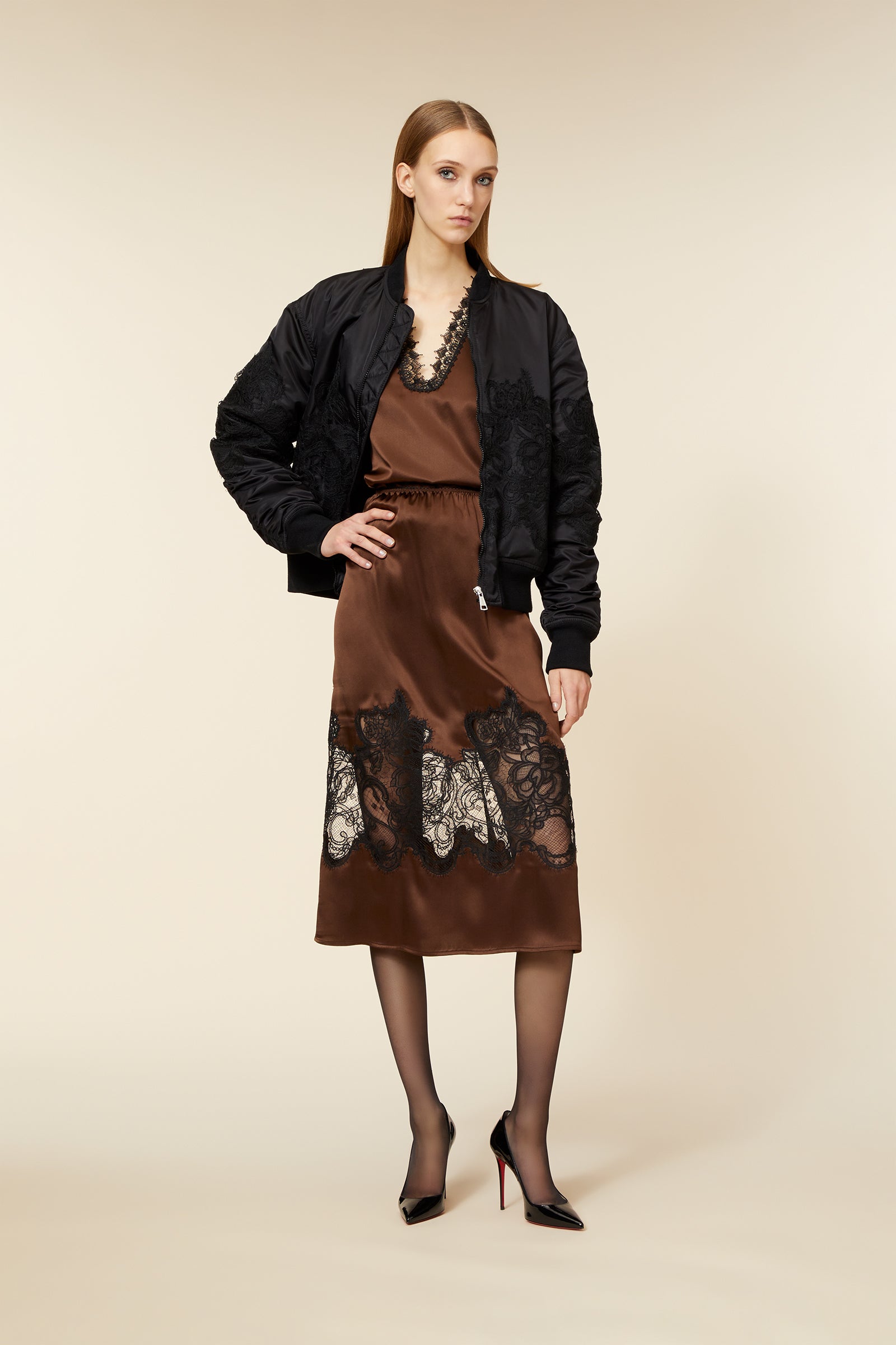 Black bomber jacket with intricate lace overlay paired with a rich brown silk dress featuring black lace detailing.