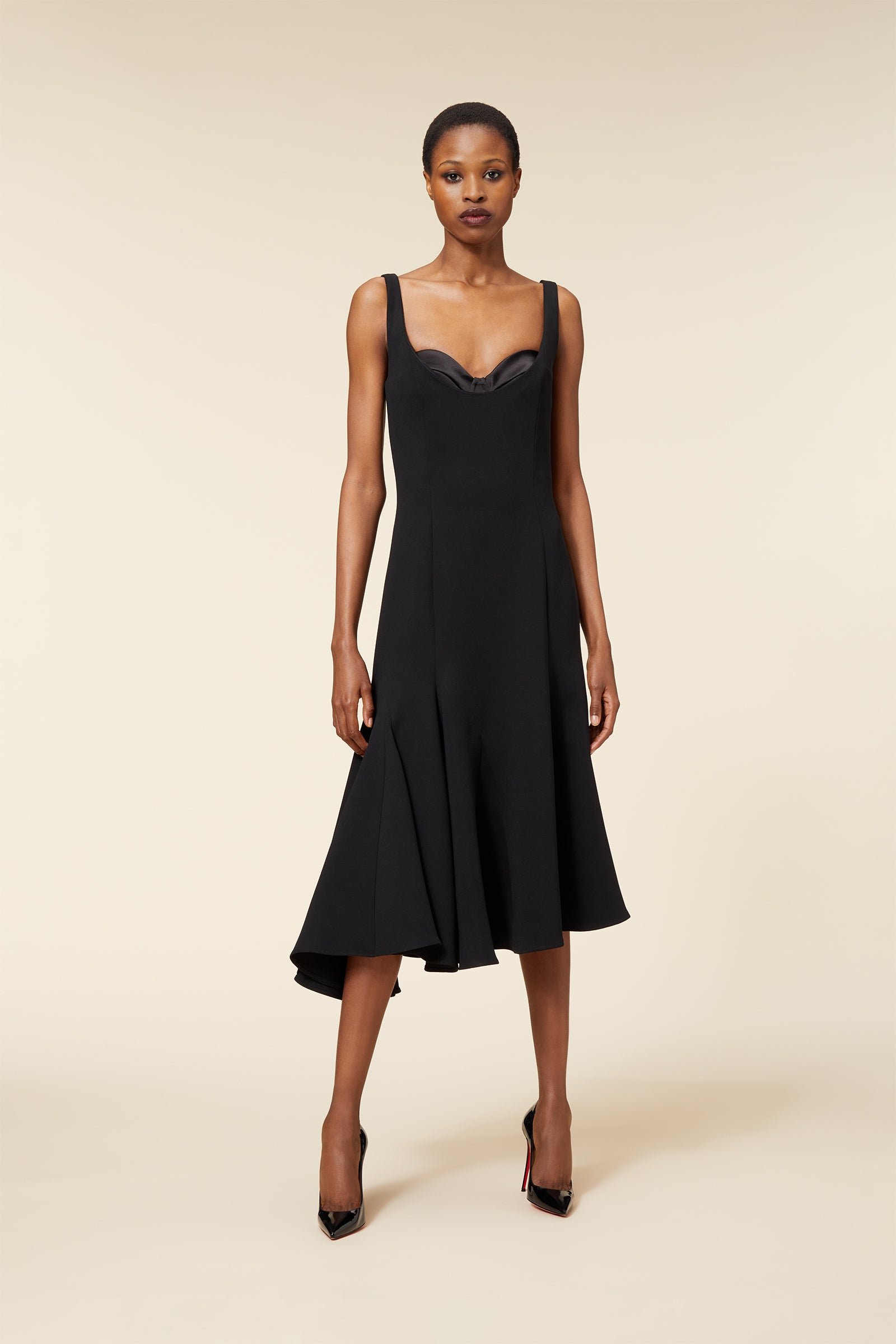 Elegant black dress with a fitted bodice and flared hem, featuring wide straps and subtle curvature details.