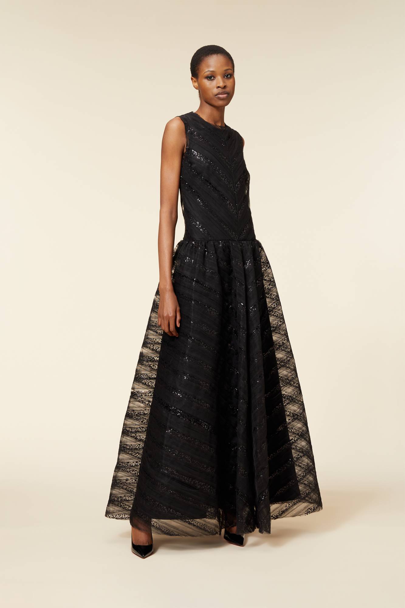 Elegant black evening gown with intricate lace and sequin detailing, sleeveless design, and flared skirt on a neutral background.