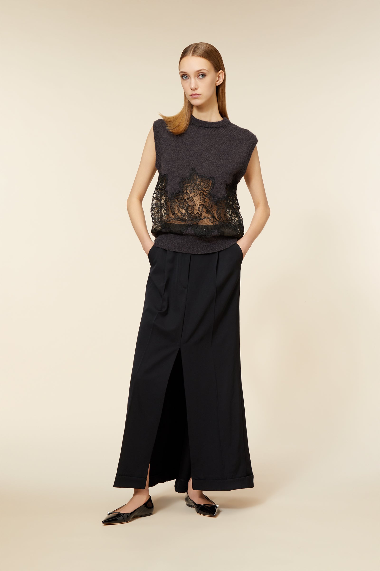 Sleeveless charcoal knit top with sheer lace panel, paired with black wide-leg trousers and elegant pointed flats.